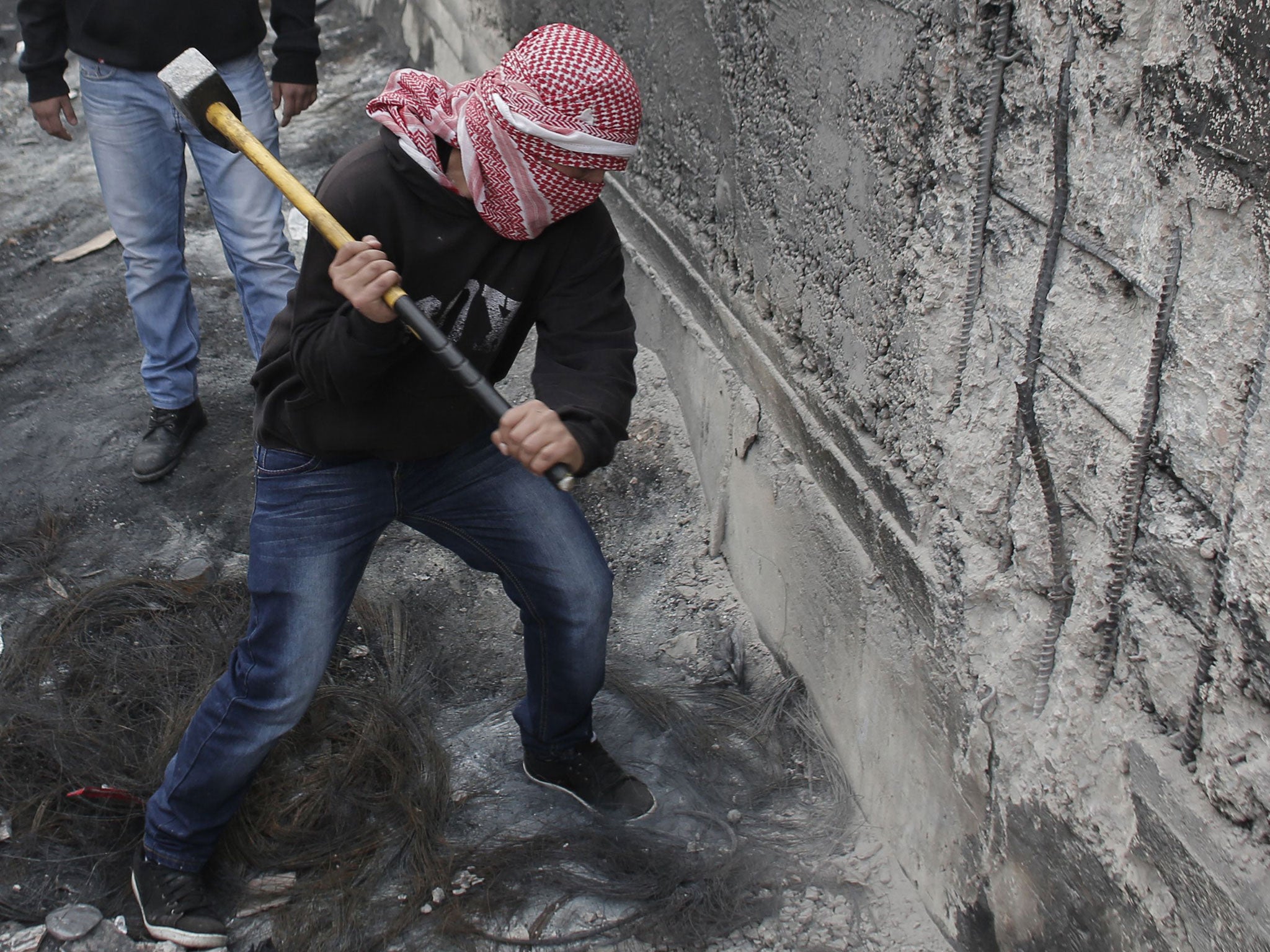 A masked Palestinian protester shows his anger after a bus driver was found hanged in his vehicle in Jerusalem