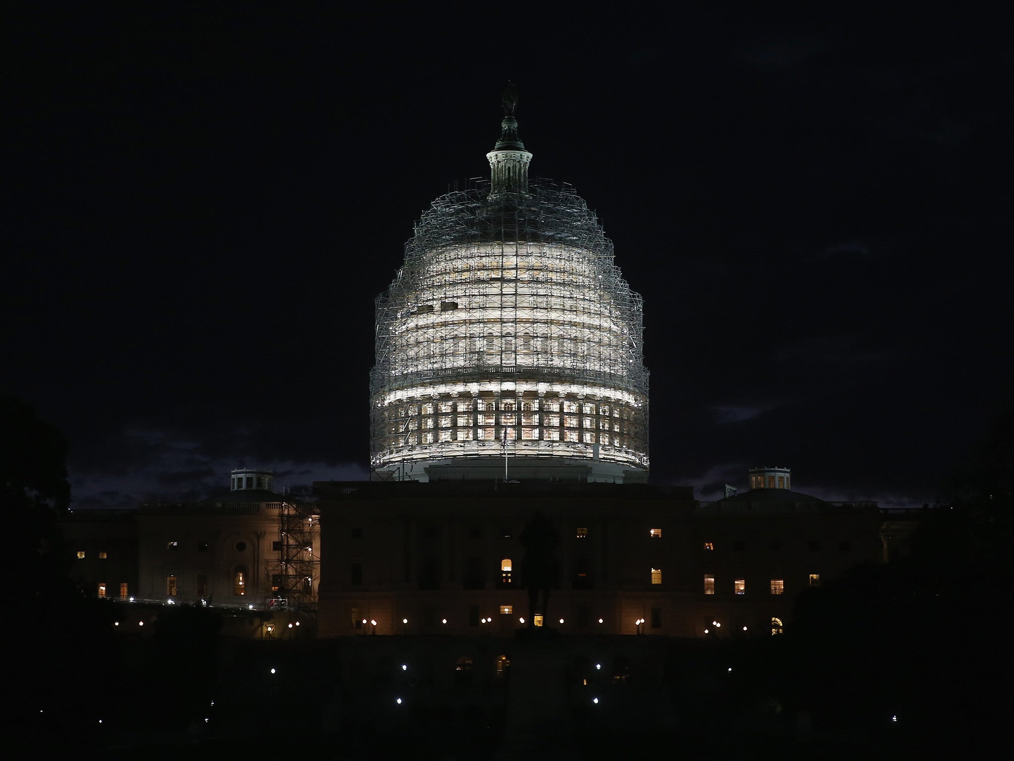 The sun begins to rise behind the dome of the US Capitol that is covered in scafollding for repairs, November 4, 2014 in Washington, DC.