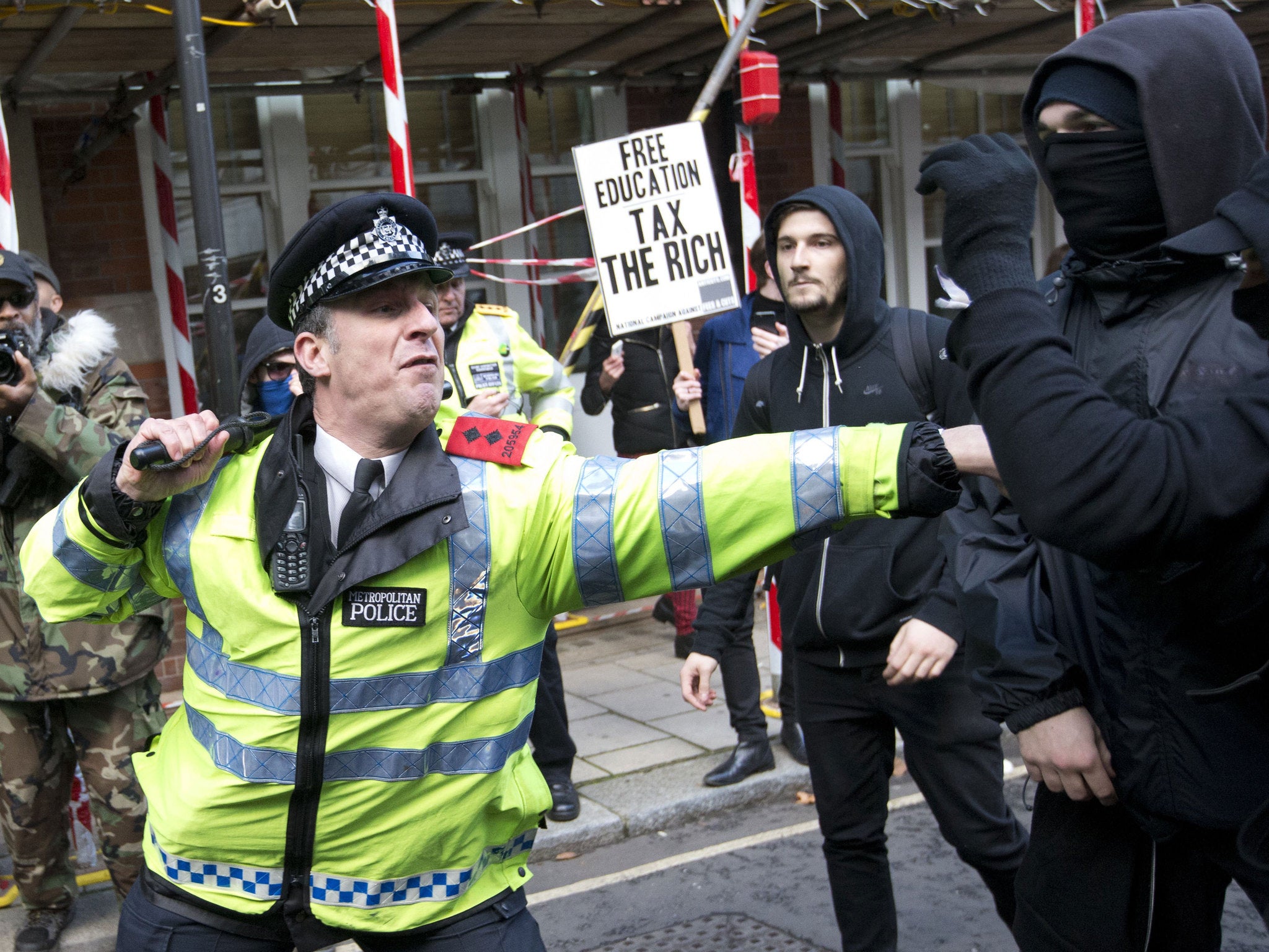 A police officer clashes with protesters outside the Conservative Campaign Headquarters