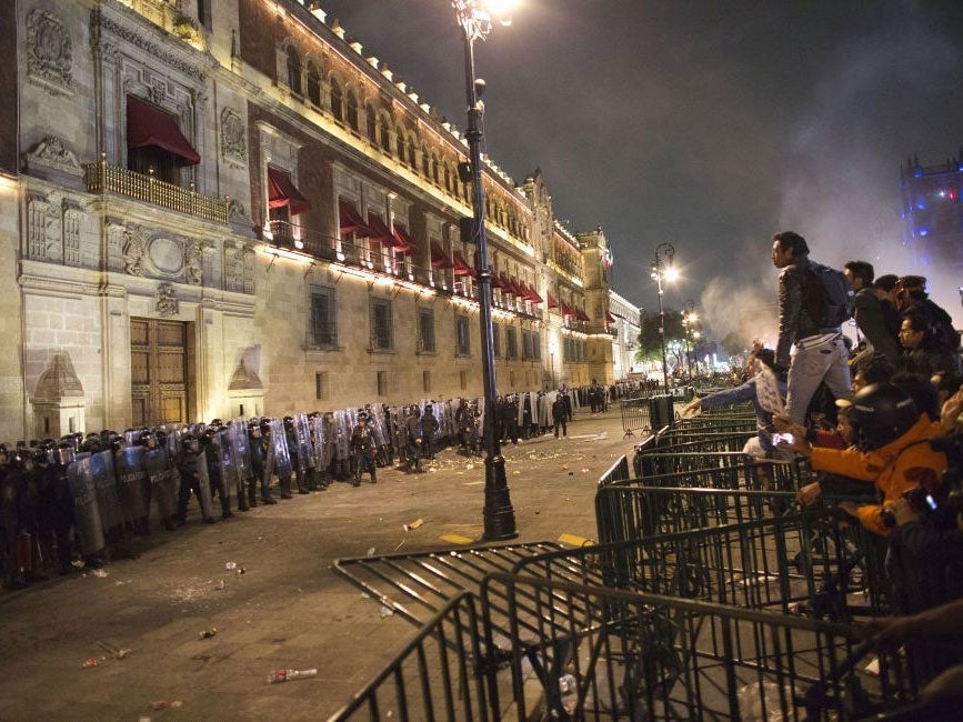 Protesters face federal police over barriers surrounding the National Palace in Mexico City, the latest in a wave of popular discontent to sweep the country