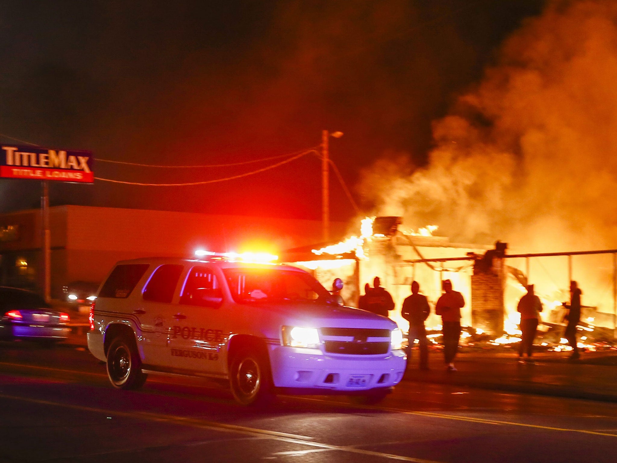 A police vehicle passes a business set ablaze by protestors in Ferguson