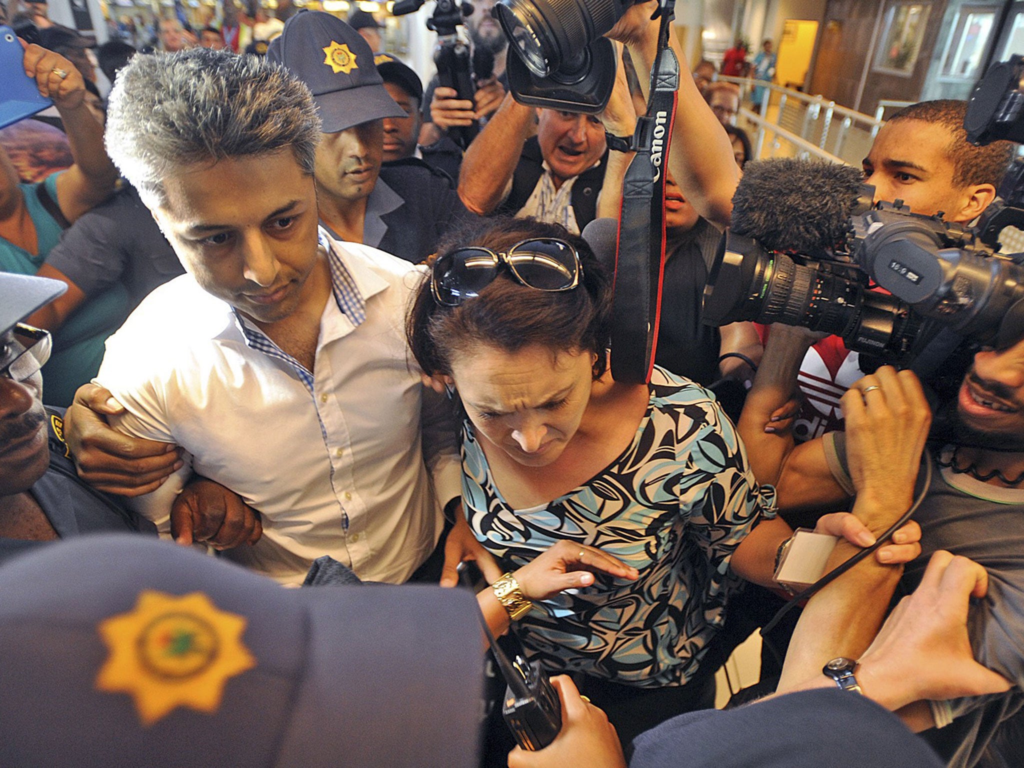 Shrien Dewani was faced with chaotic scenes as he walked hurriedly through Cape Town International Airport this morning