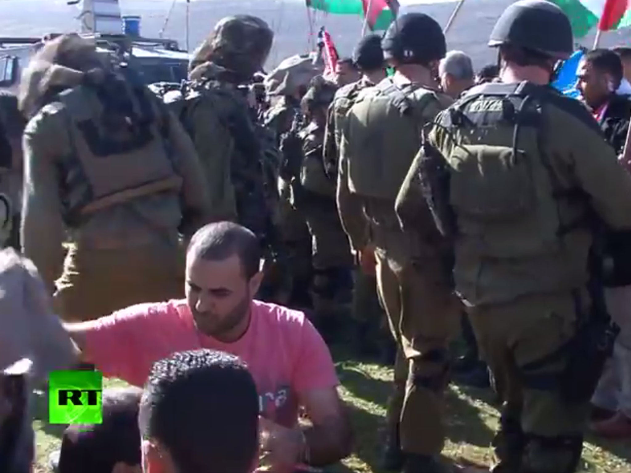 Two protesters, separated from the wider group by a line of Israeli soldiers, put a coat around Abu Ein in the aftermath of the incident (RT)