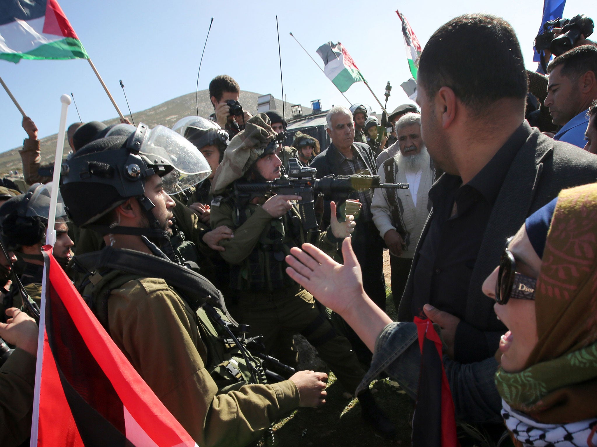 An Israeli soldier aims his weapon at protesters as forces try to disperse a demonstration in West Bank