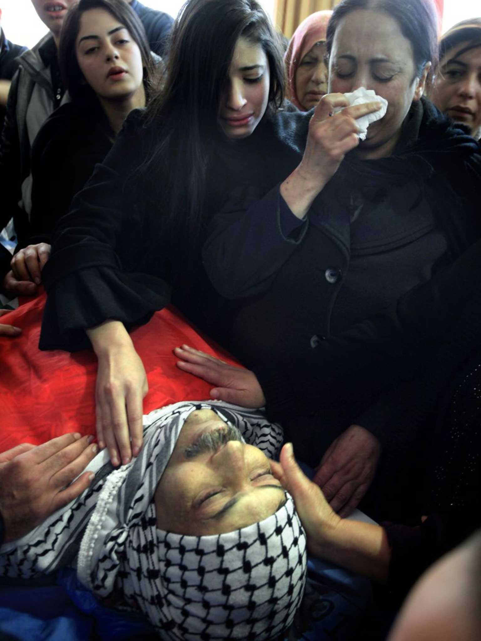 The widow (R) and the daughter (C) of senior Palestinian official Ziad Abu Ein mourn over his body