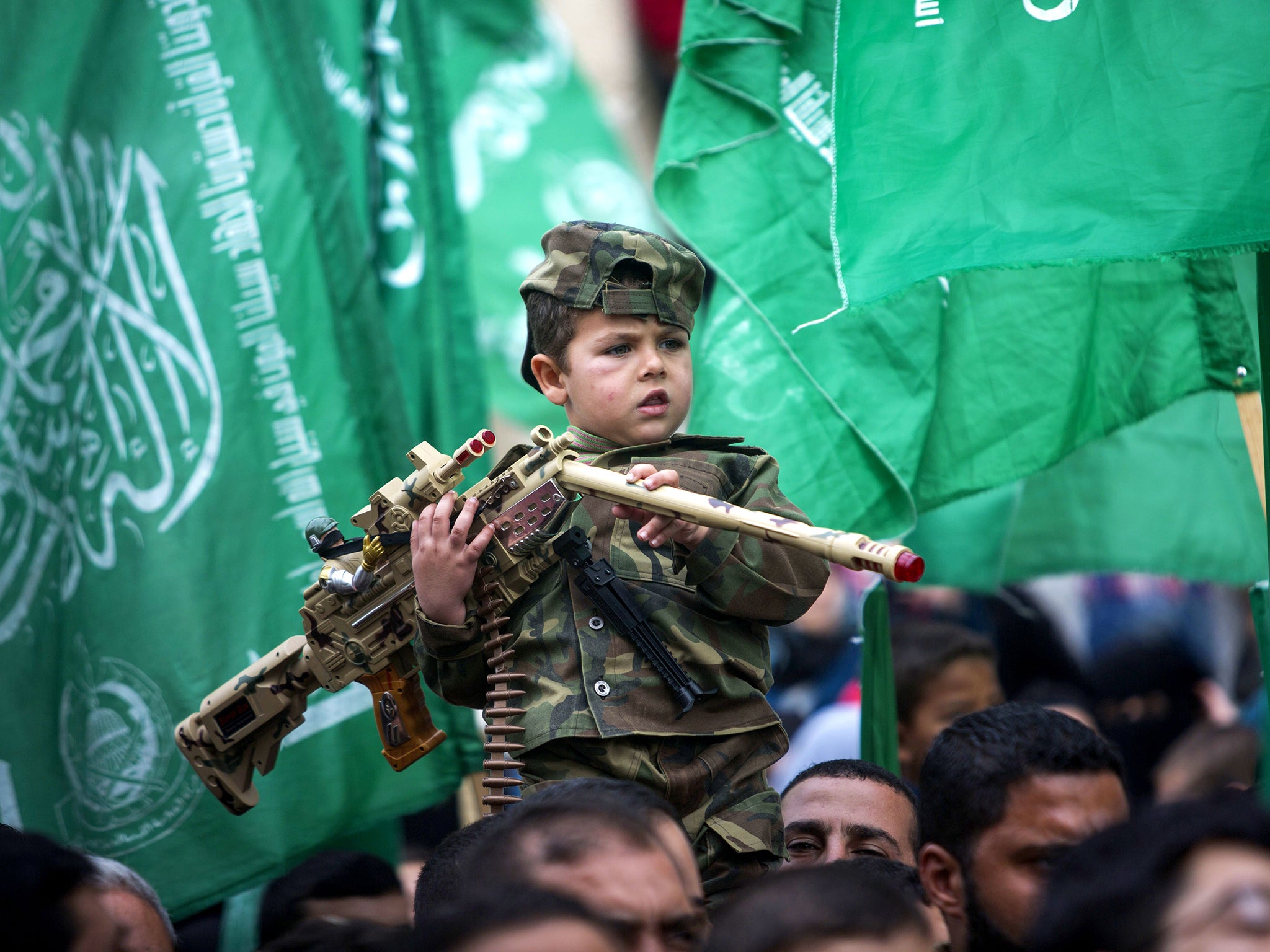 A Palestinian boy armed with a toy assault rifle amidst the rally