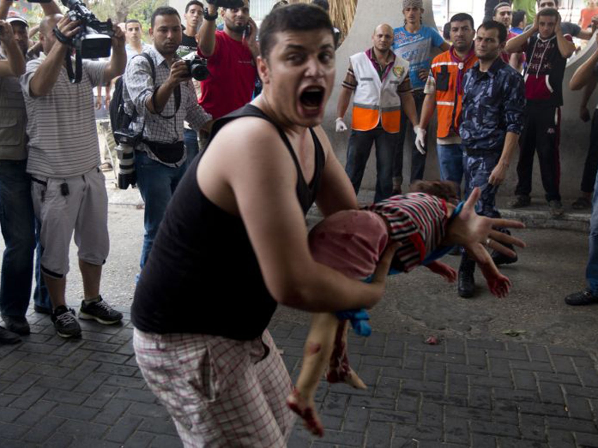 A Palestinian man carries the body of his daughter, who was killed during Israeli shelling, outside the al-Shifa hospital in Gaza City