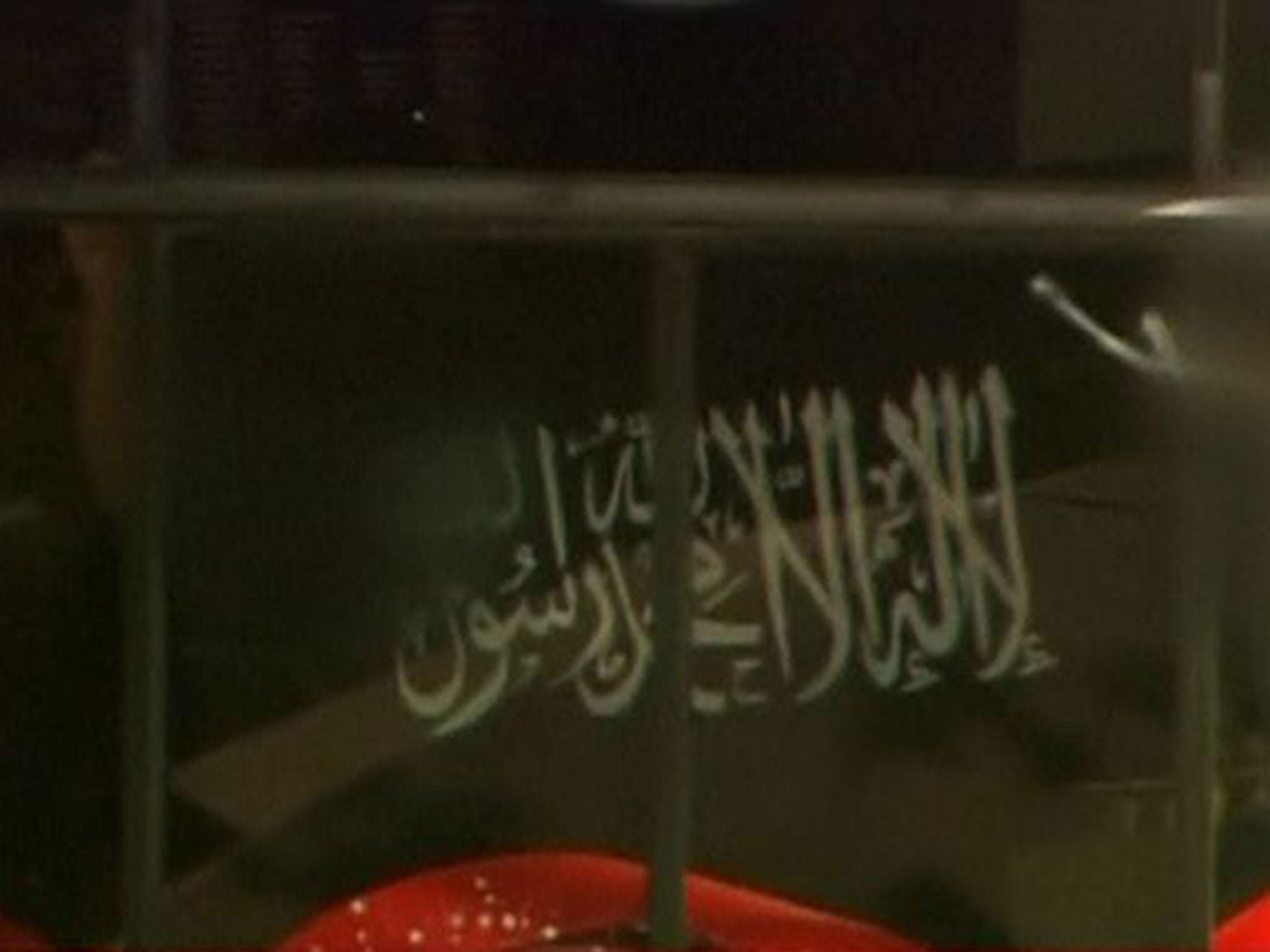 A black flag with white Arabic writing is held up at the window of the Lindt cafe