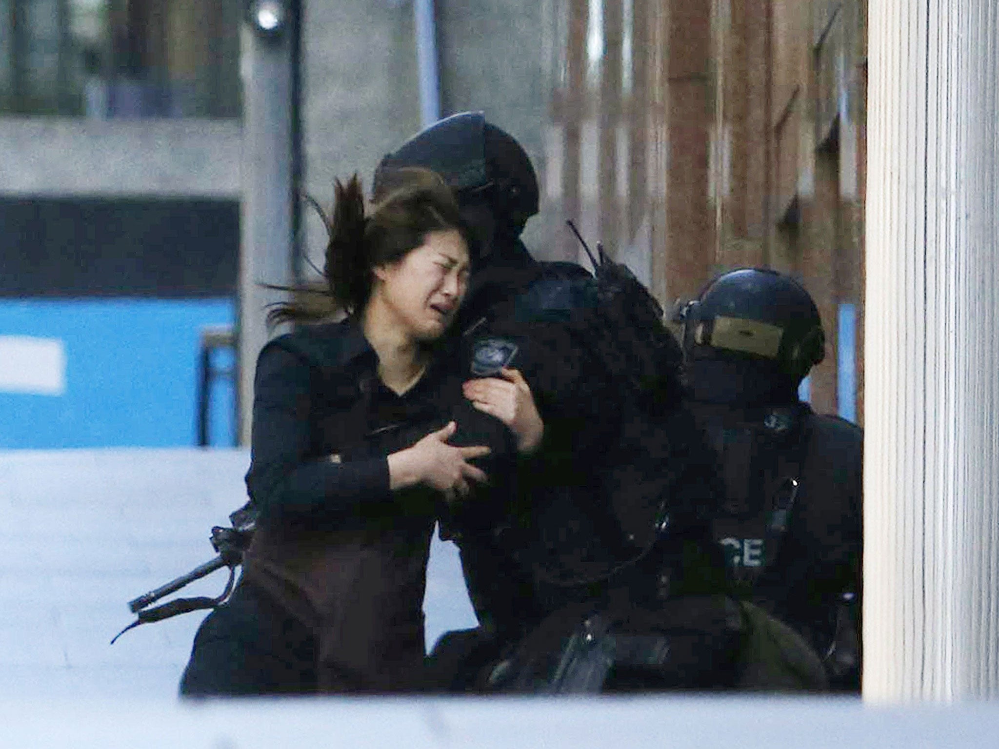 A hostage runs towards a police officer outside a cafe, where other hostages are being held in Sydney