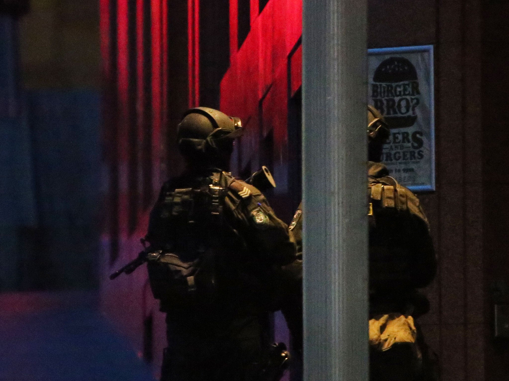 Armed tactical response police personnel stand watch into the evening near a cafe under siege by a gunman at Martin Place