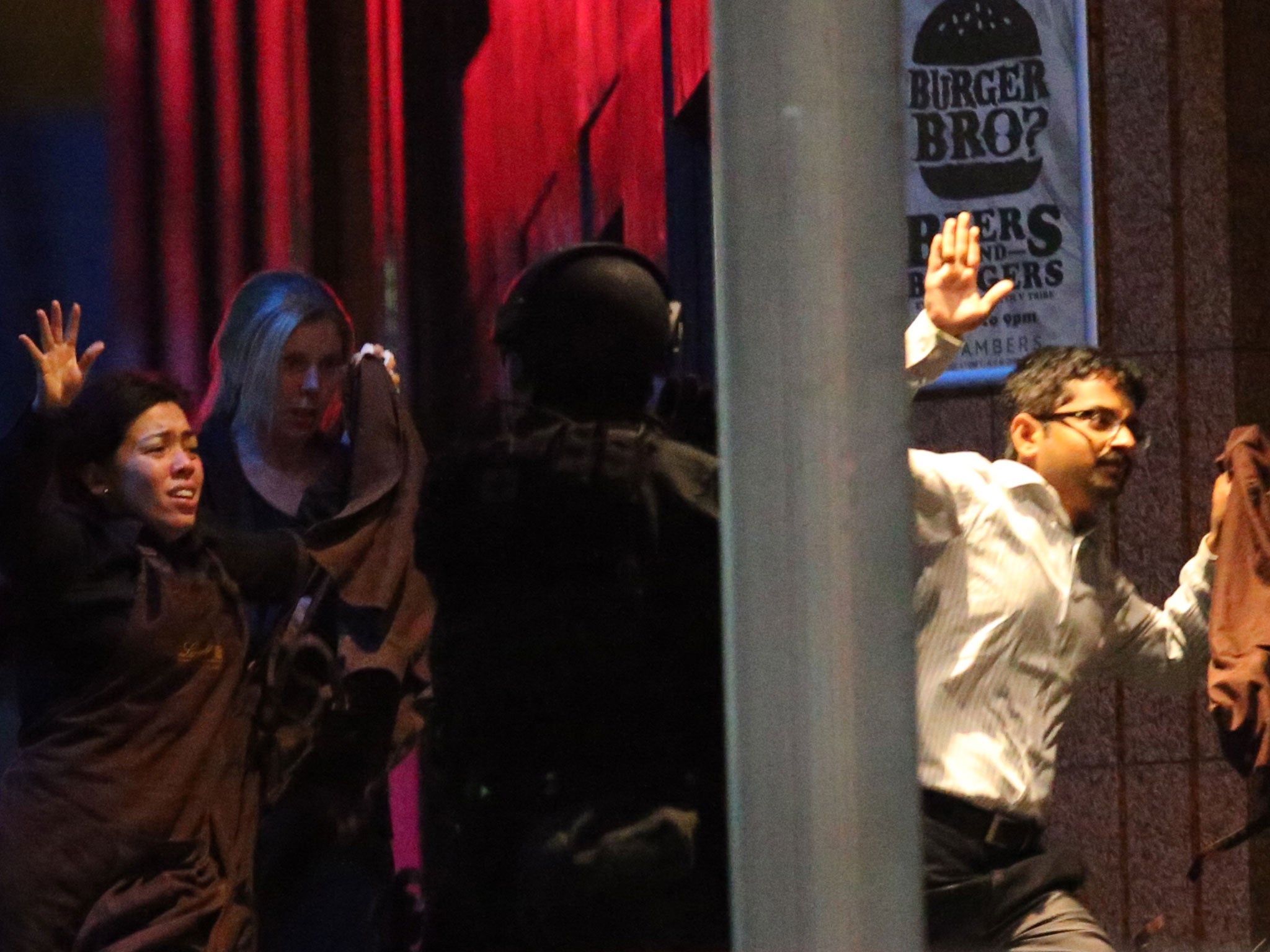 Hostages run towards armed tactical responce police as they run to freedom from a cafe under siege at Martin Place in the central business district of Sydney