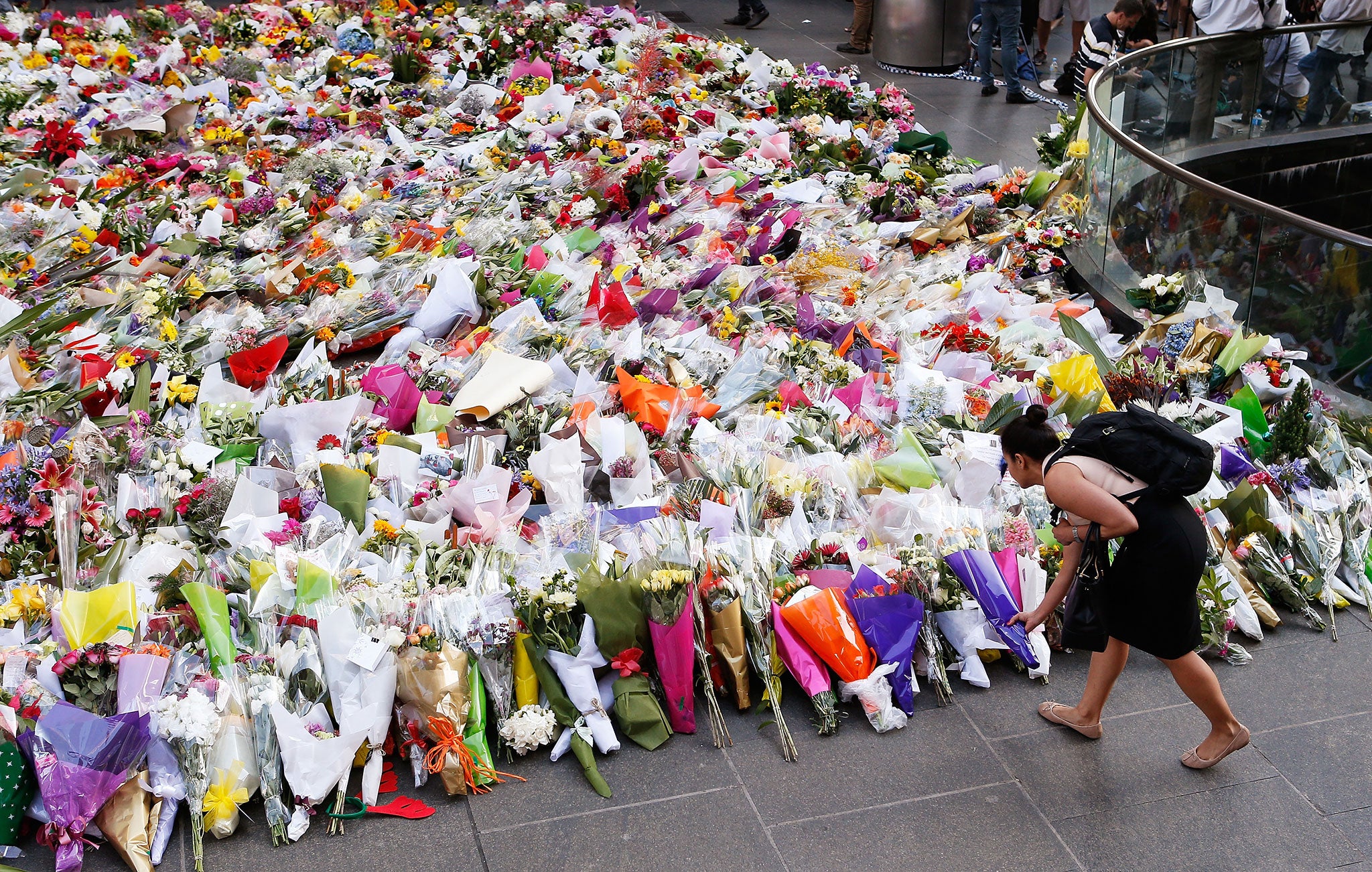 A woman places flowers as a mark of respect for the victims of Martin Place siege in Sydney