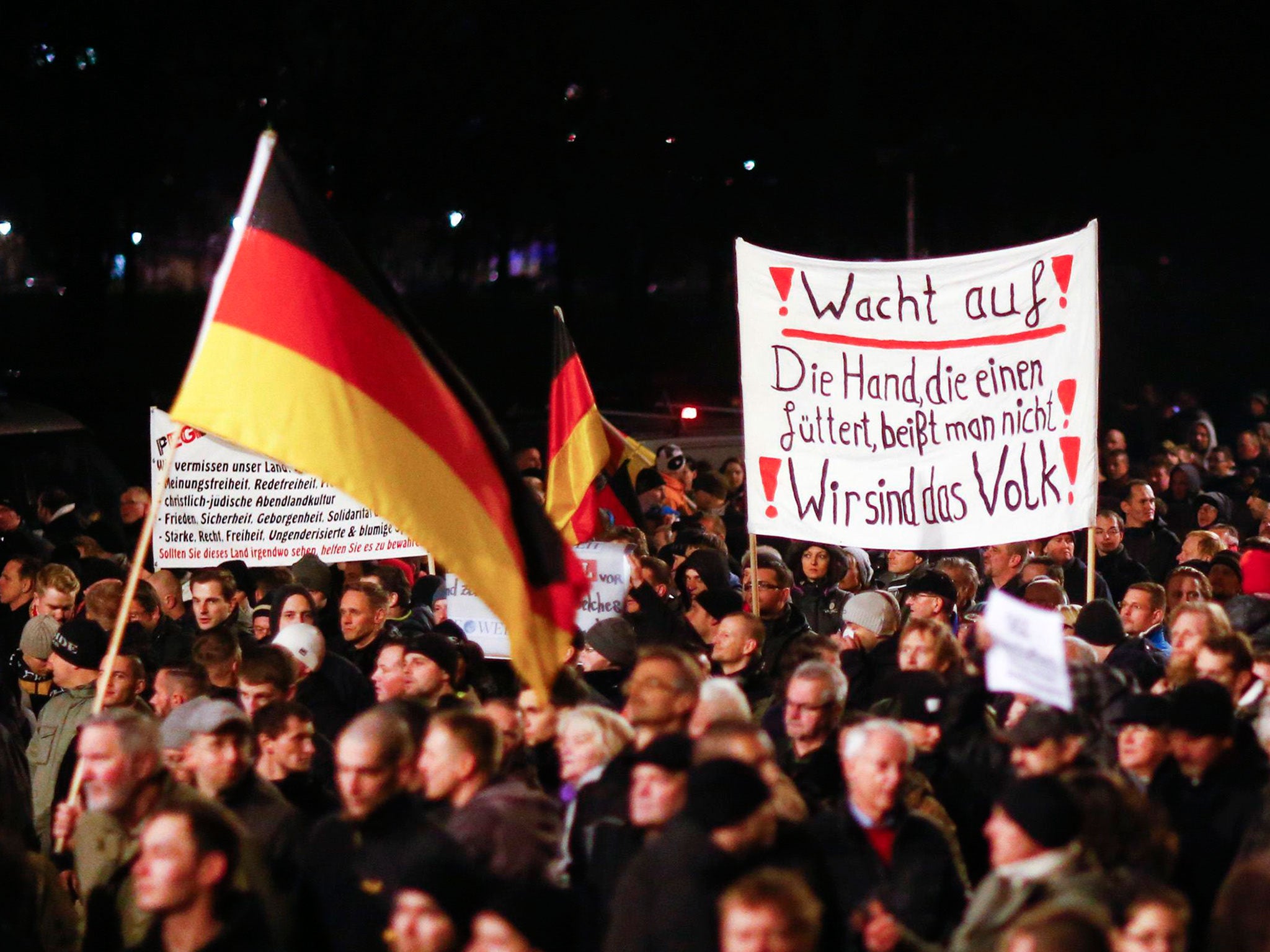 Participants hold German national flags and a banner during a demonstration called by anti-immigration group PEGIDA