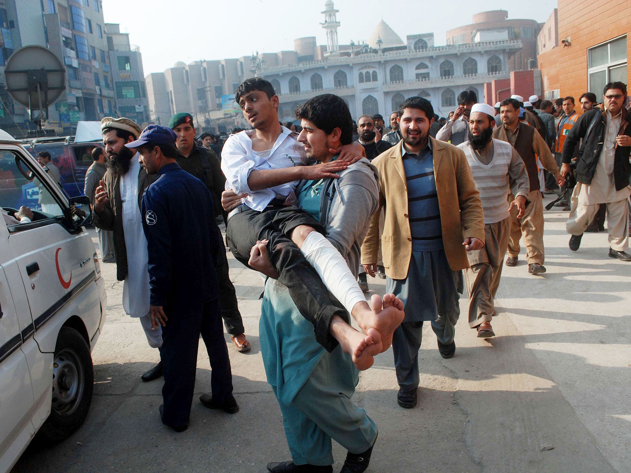 A man carries a student, who was injured during an attack by Taliban gunmen on the Army Public School, after he received treatment at a hospital in Peshawar