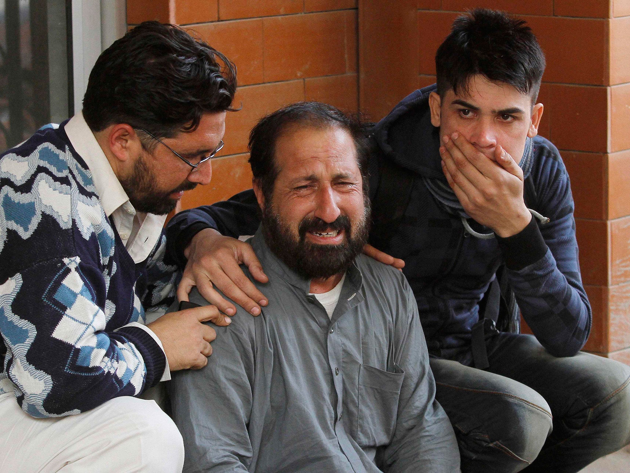 Relatives of a student, who was injured during an attack by Taliban gunmen on the Army Public School, comfort each other outside Lady Reading Hospital in Peshawar