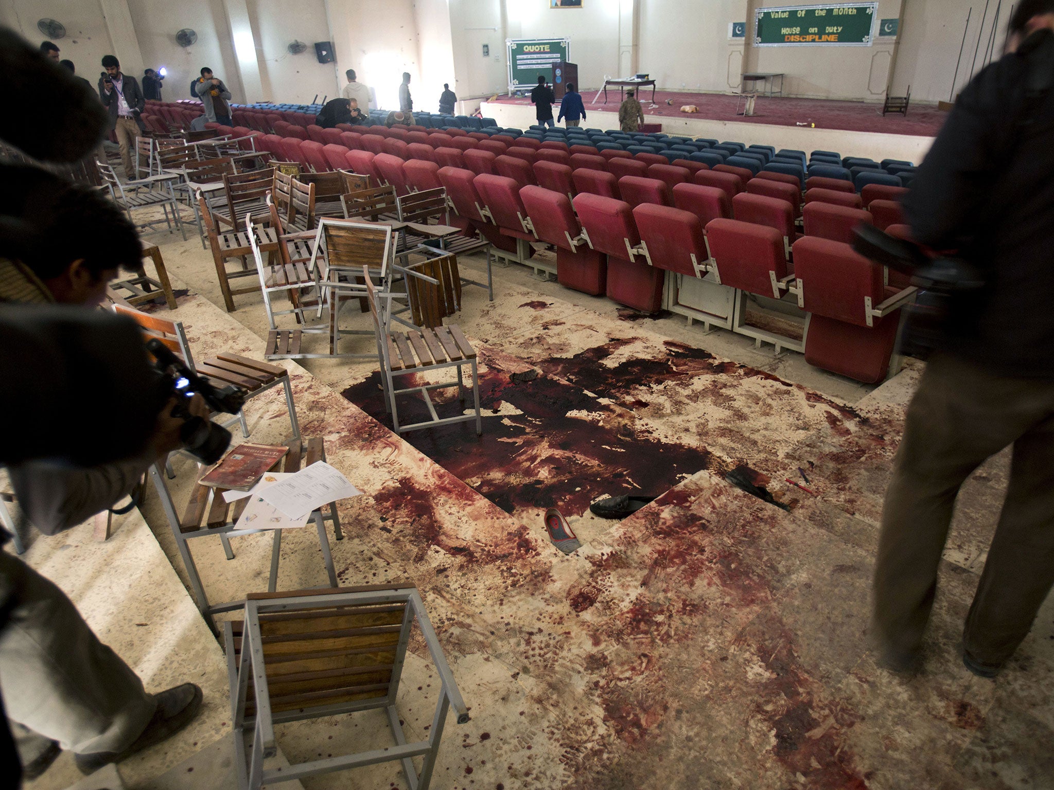 Pakistani video journalists film inside the auditorium of the Army Public School a day after an attack by the Taliban, in Peshawar, Pakistan