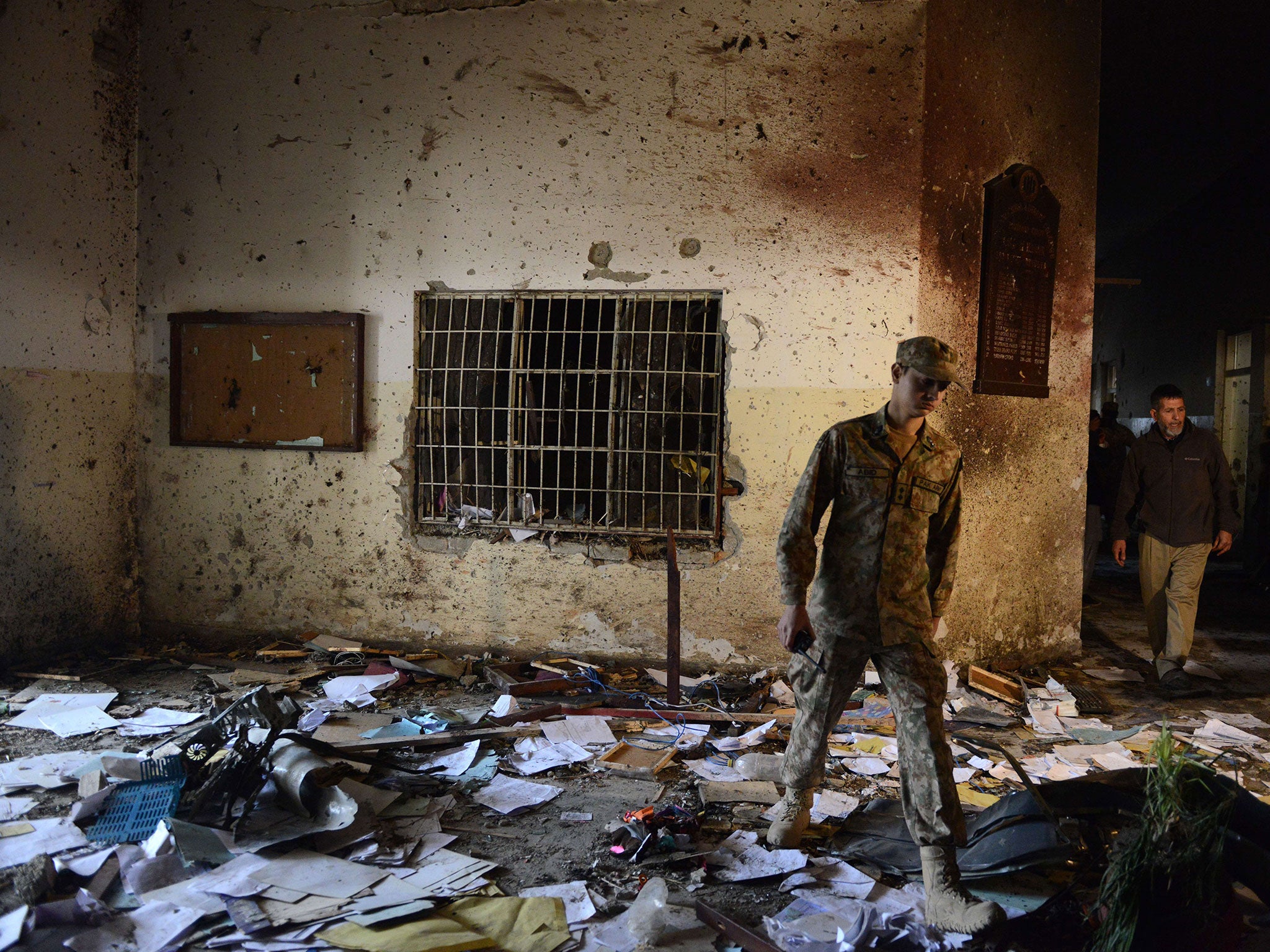 A Pakistani soldier walks amidst the debris the day after the Taliban attack at the school in Peshawar