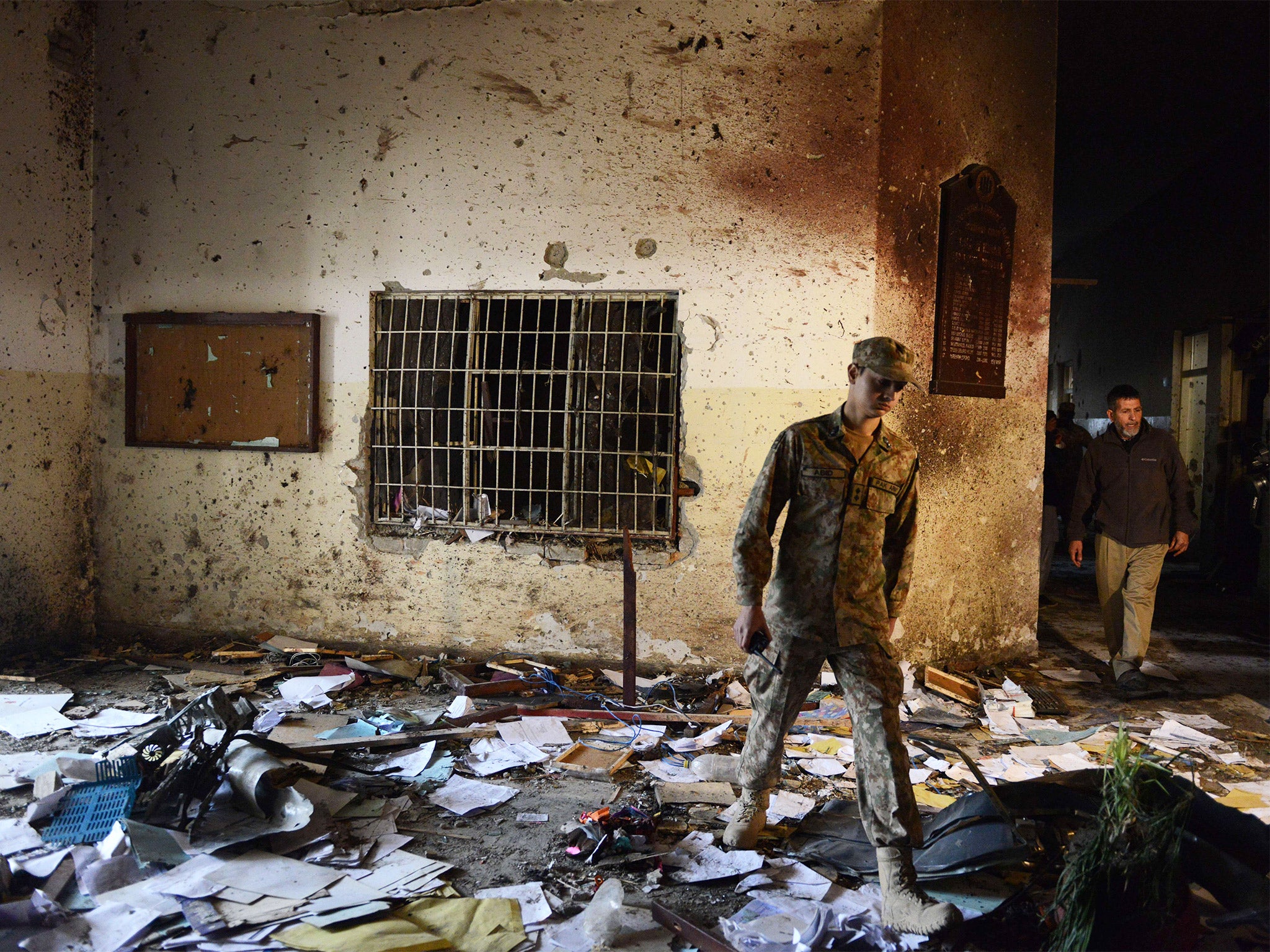 A Pakistani soldier walks amidst the debris at the army-run school in Peshawa