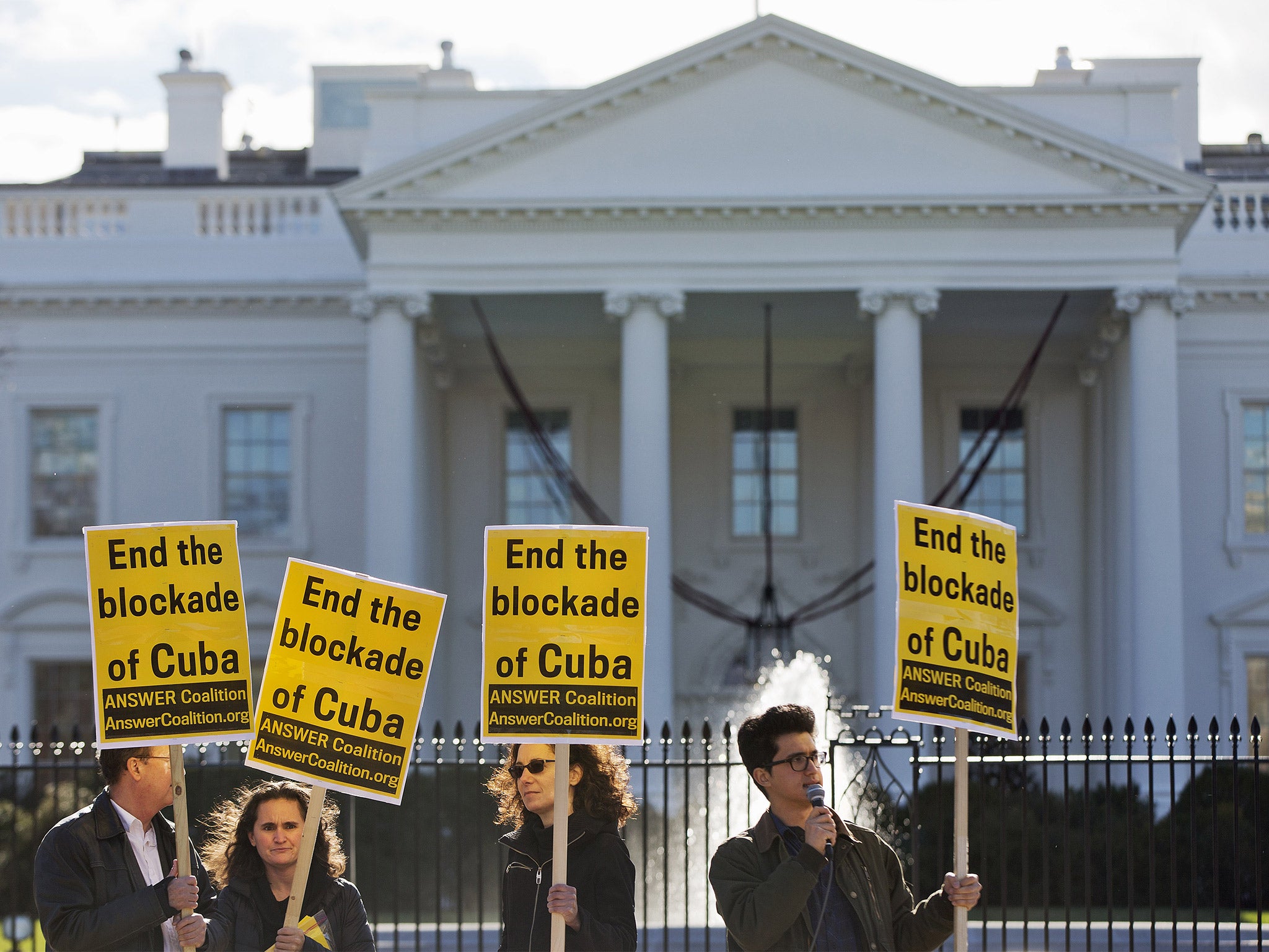 Demonstrators hold signs urging the US to 'End the blockade of Cuba,' outside the White House in Washington on Wednesday