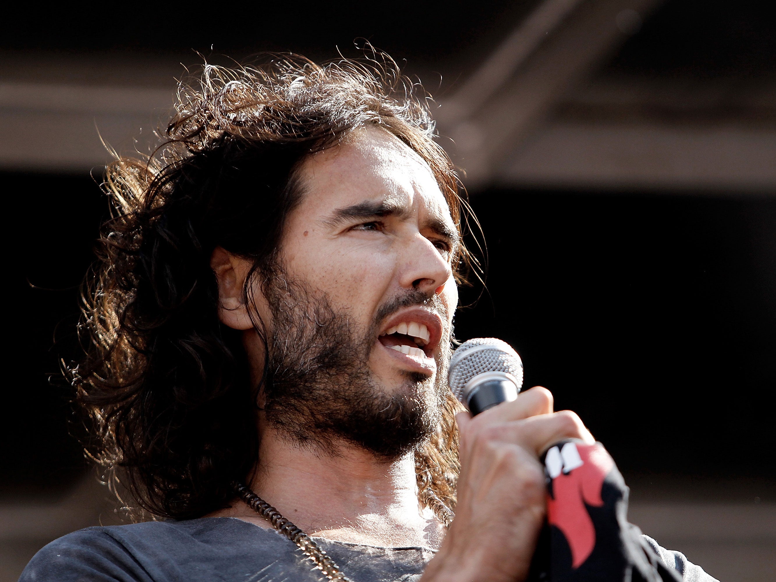 Comedian Russell Brand speaks to a crowd of thousands of demonstrators that gathered in Parliament Square, London