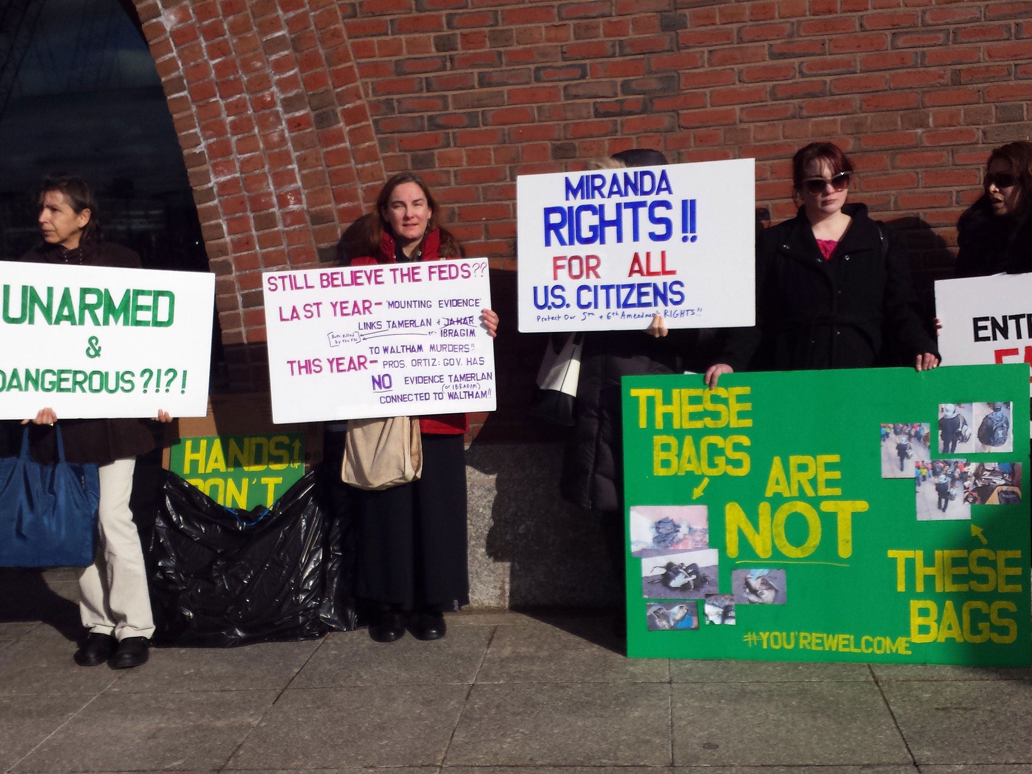 Protesters hold signs in front of the John Joseph Moakley US Federal Courthouse in Boston Massaschusetts