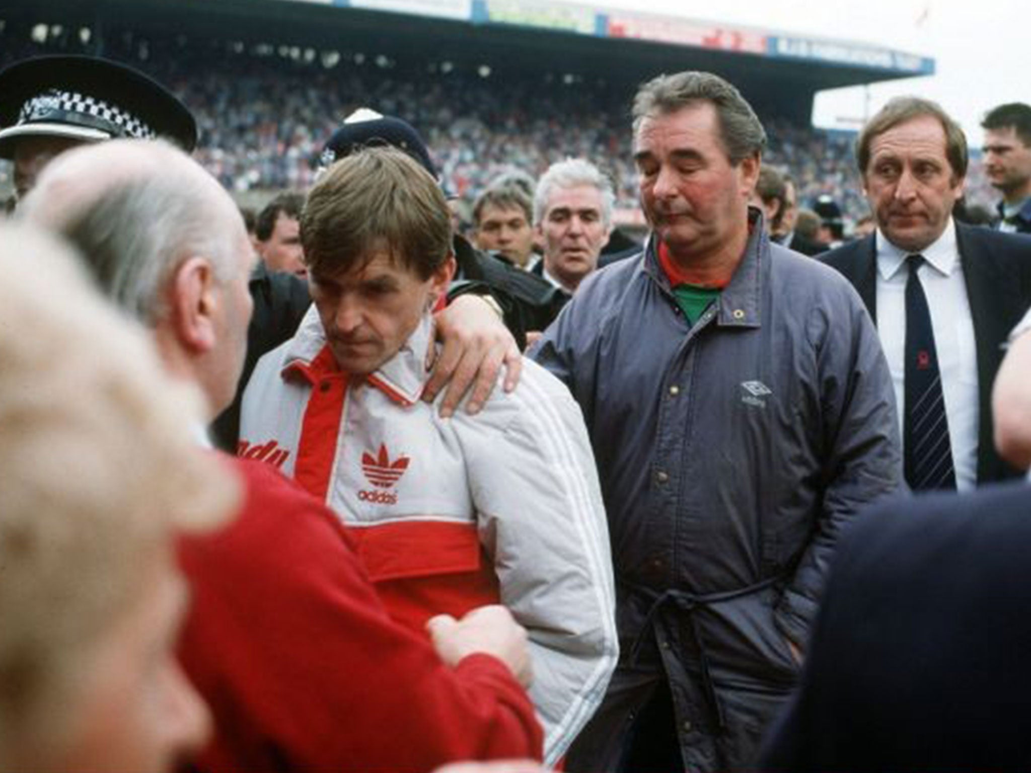 Kenny Dalglish is comforted by a police officer as he and Nottingham Forest Manager Brian Clough leave Hillborough on 15 April 1989