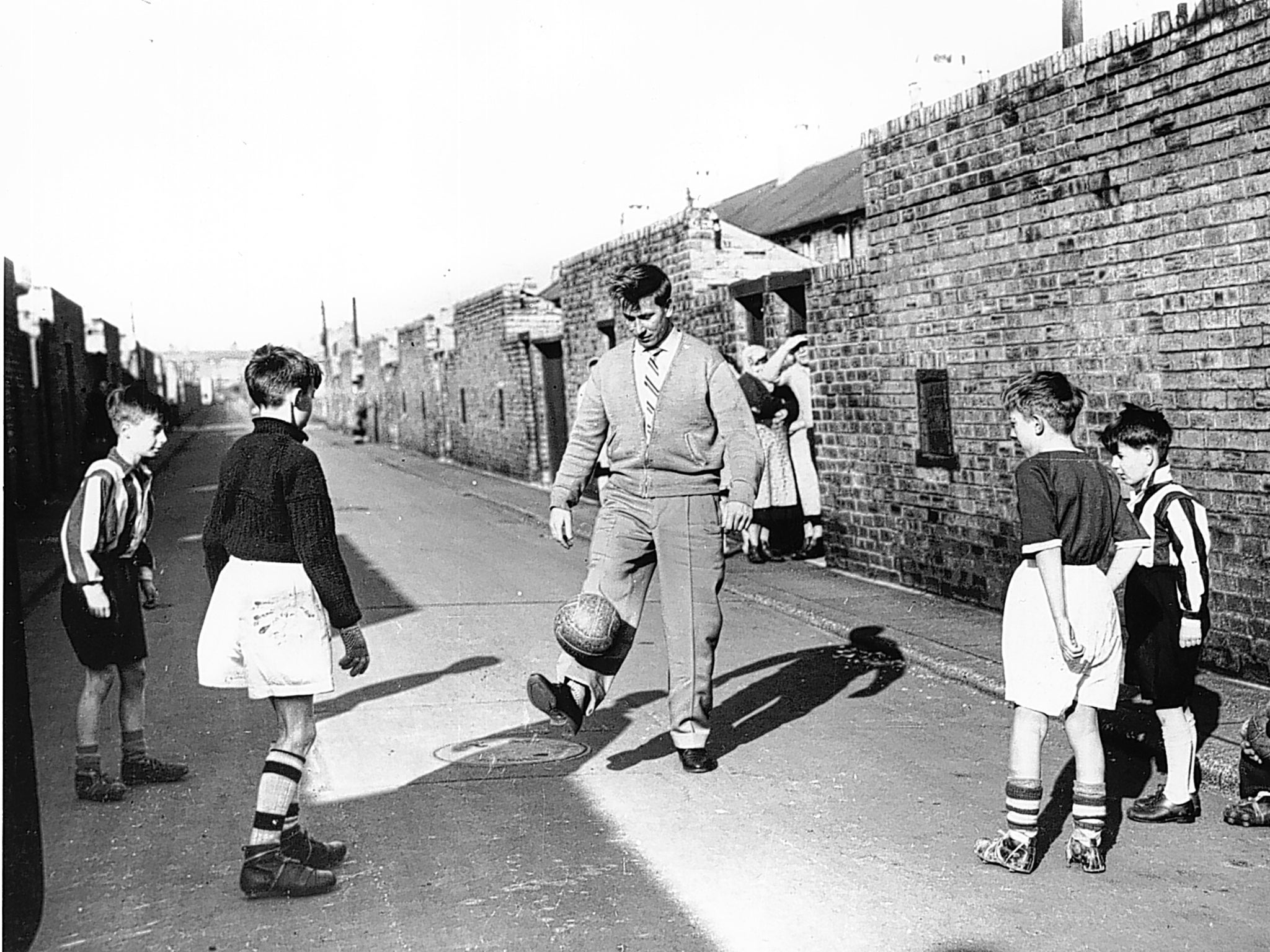 Bobby Charlton entertains some young fans in the backyard of his home on Beatrice Street, Ashington, Northumberland following the Munich Air Disaster