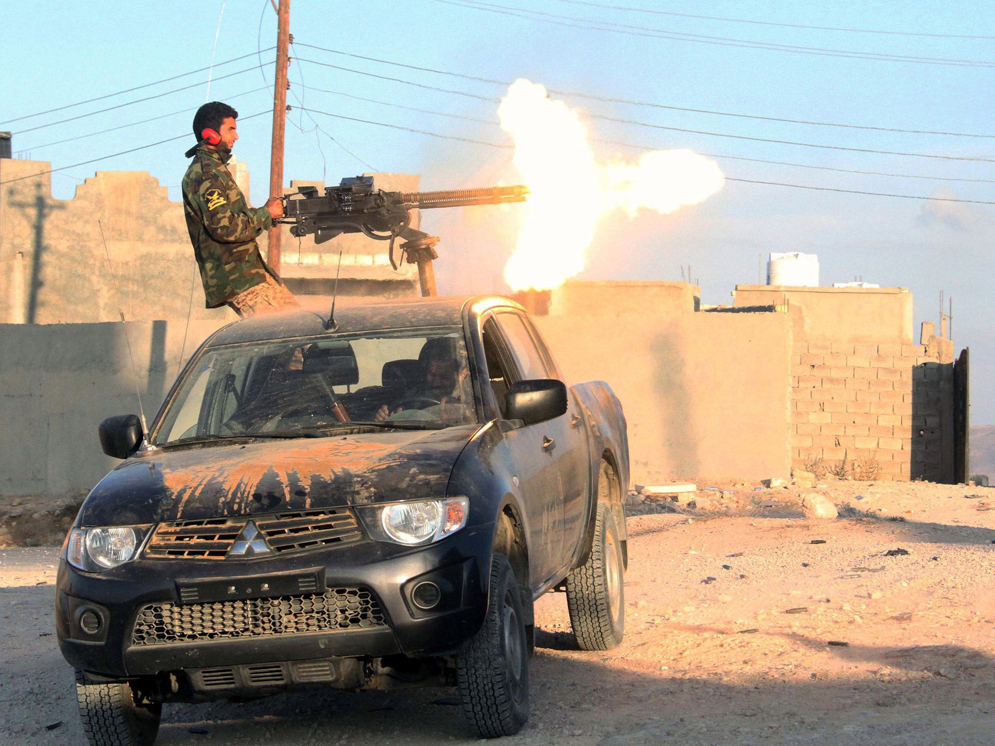 A fighter of Libya's Fajr Libya group (Libyan Dawn) fires his gun during clashes in the hill village of Kikla, southwest of Tripoli, in October
