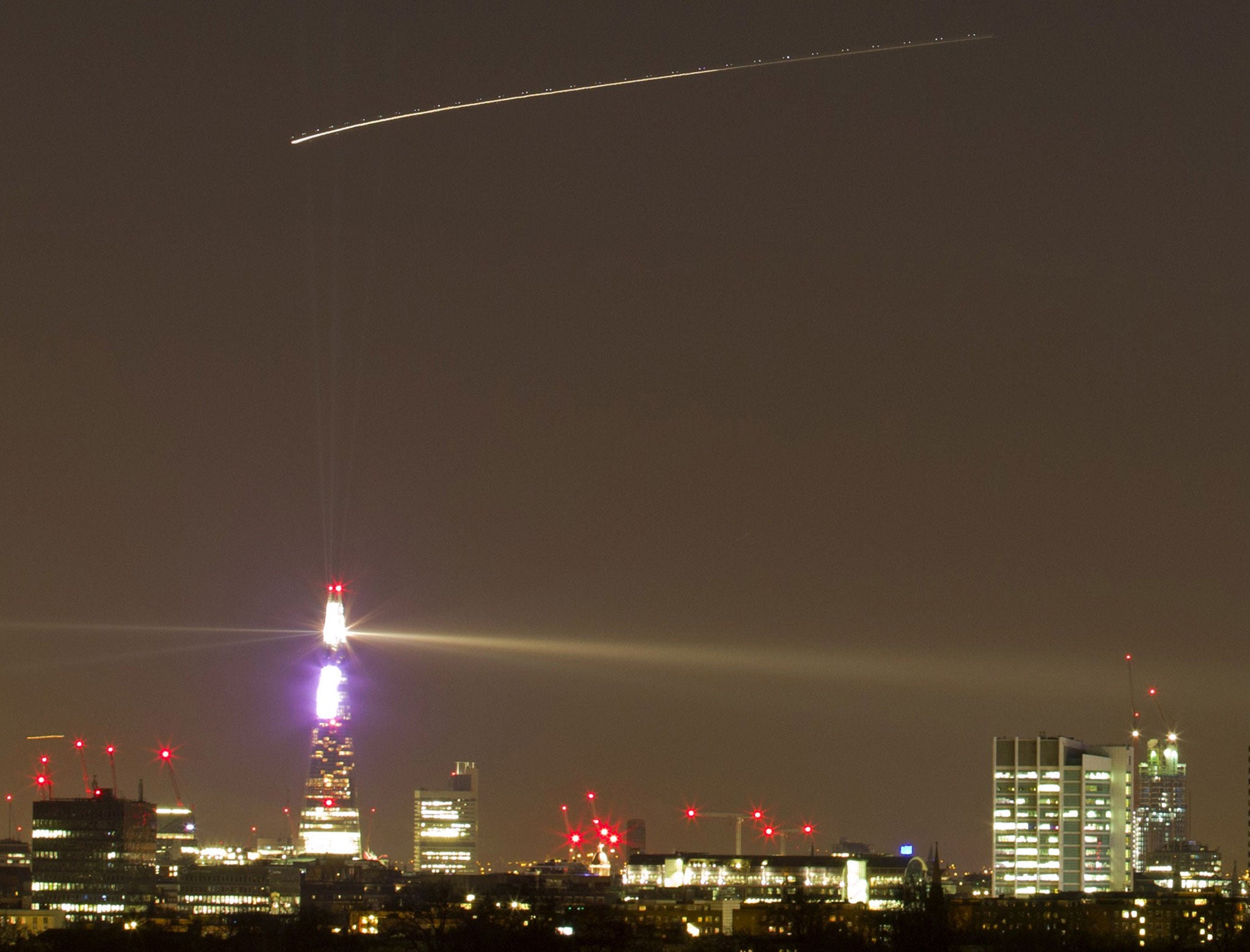 The path of The International Space Station (top straight line) is seen from central London on Christmas Eve. The trail of an aircraft on its way to Heathrow is seen below