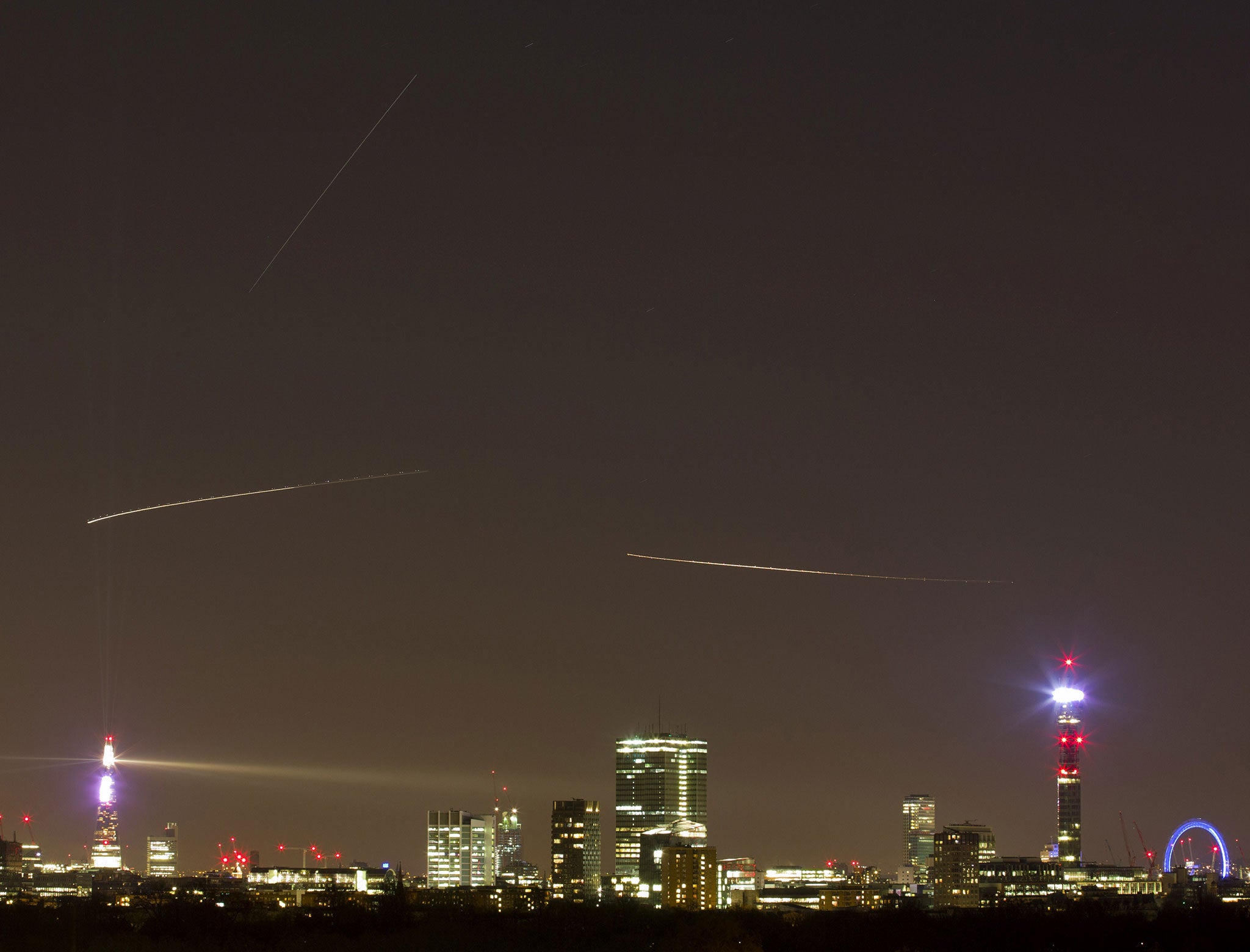 The path of The International Space Station (top straight line) is seen from central London on December 24, 2014. The trails of two aircraft on their way to Heathrow are seen below