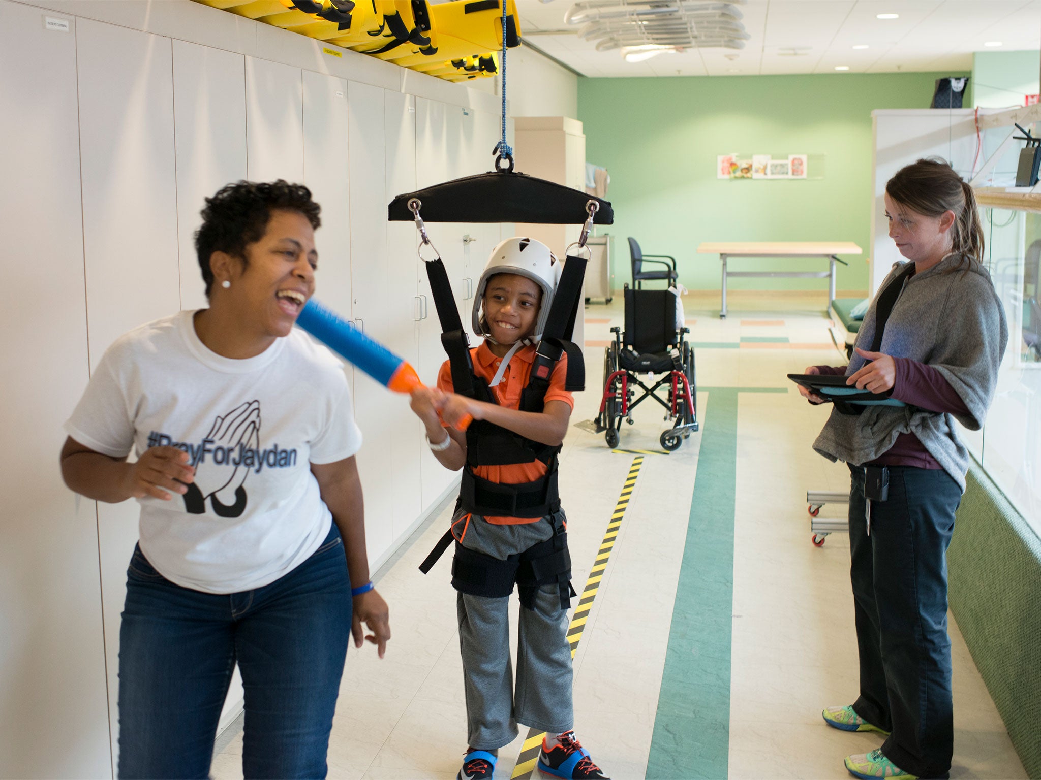 Jaydan Stancil, 9, playfully bats his mother, Monique Nichols, during one of his physical therapy sessions with physical therapist Sara Gassenmeyer