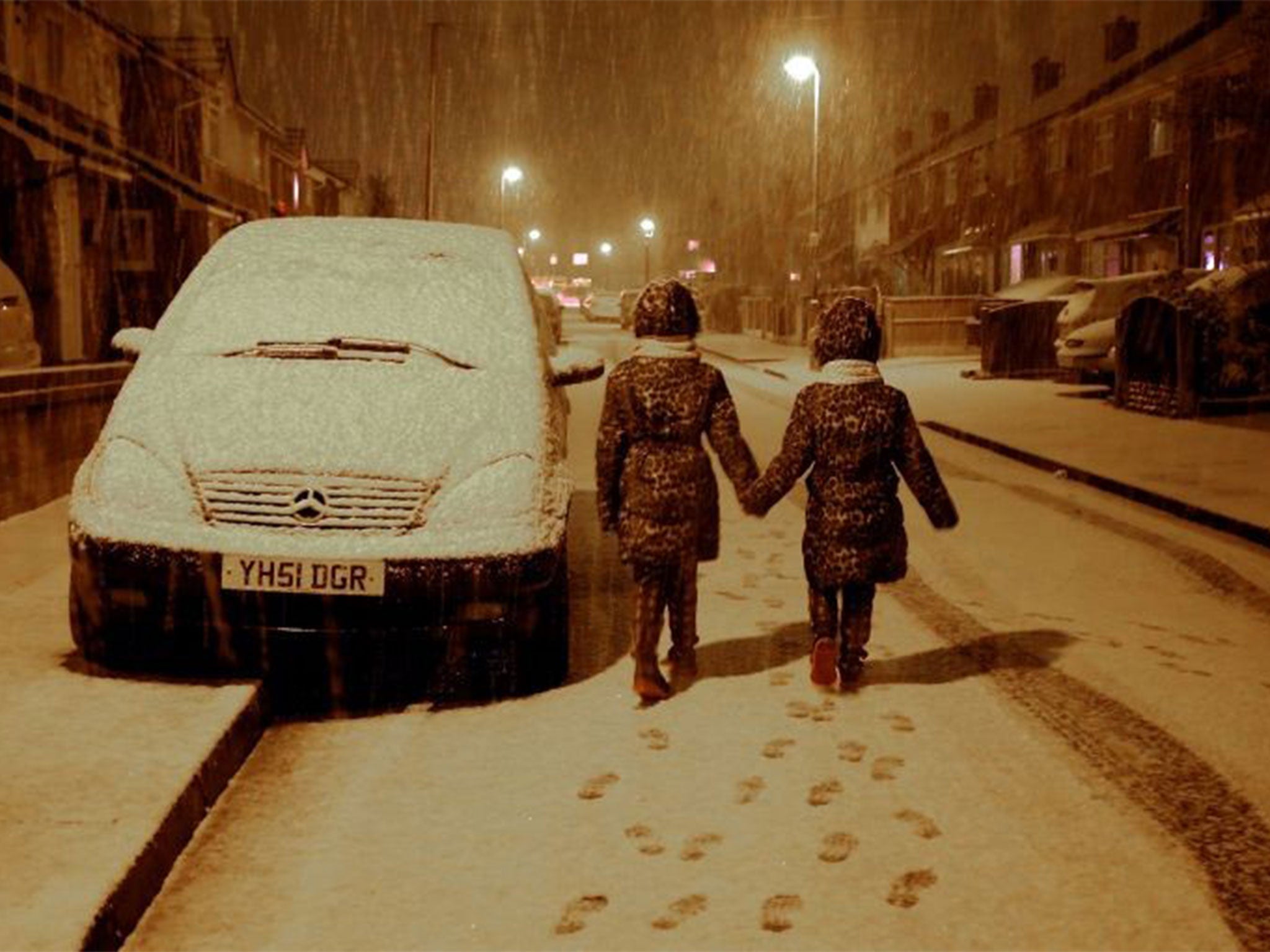 Maisy Byrne, aged nine, (left) and sister Lulu Byrne, aged seven, have fun as snow falls on Boxing Day in Gateacre, Liverpool