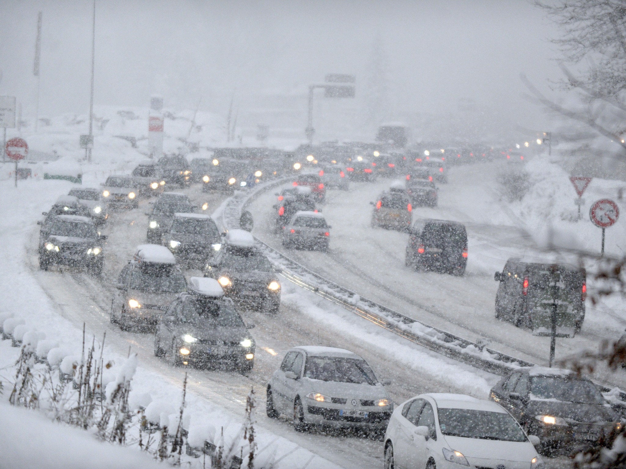 Snow fall as cars move bumper-to-bumper along the motorway near Albertville, on December 27, 2014 as they make their way into the Tarentaise valley in the heart of the French Alps