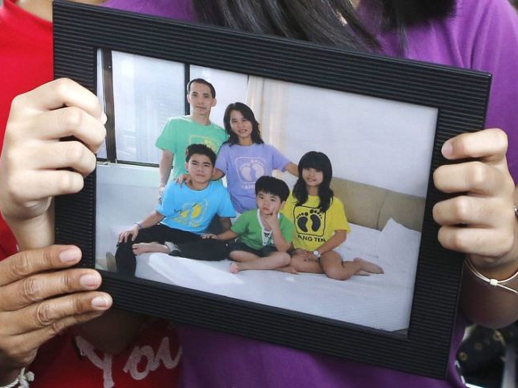 Relatives hold a picture of the Herumanto Tanus family as they wait for news from the missing AirAsia plane