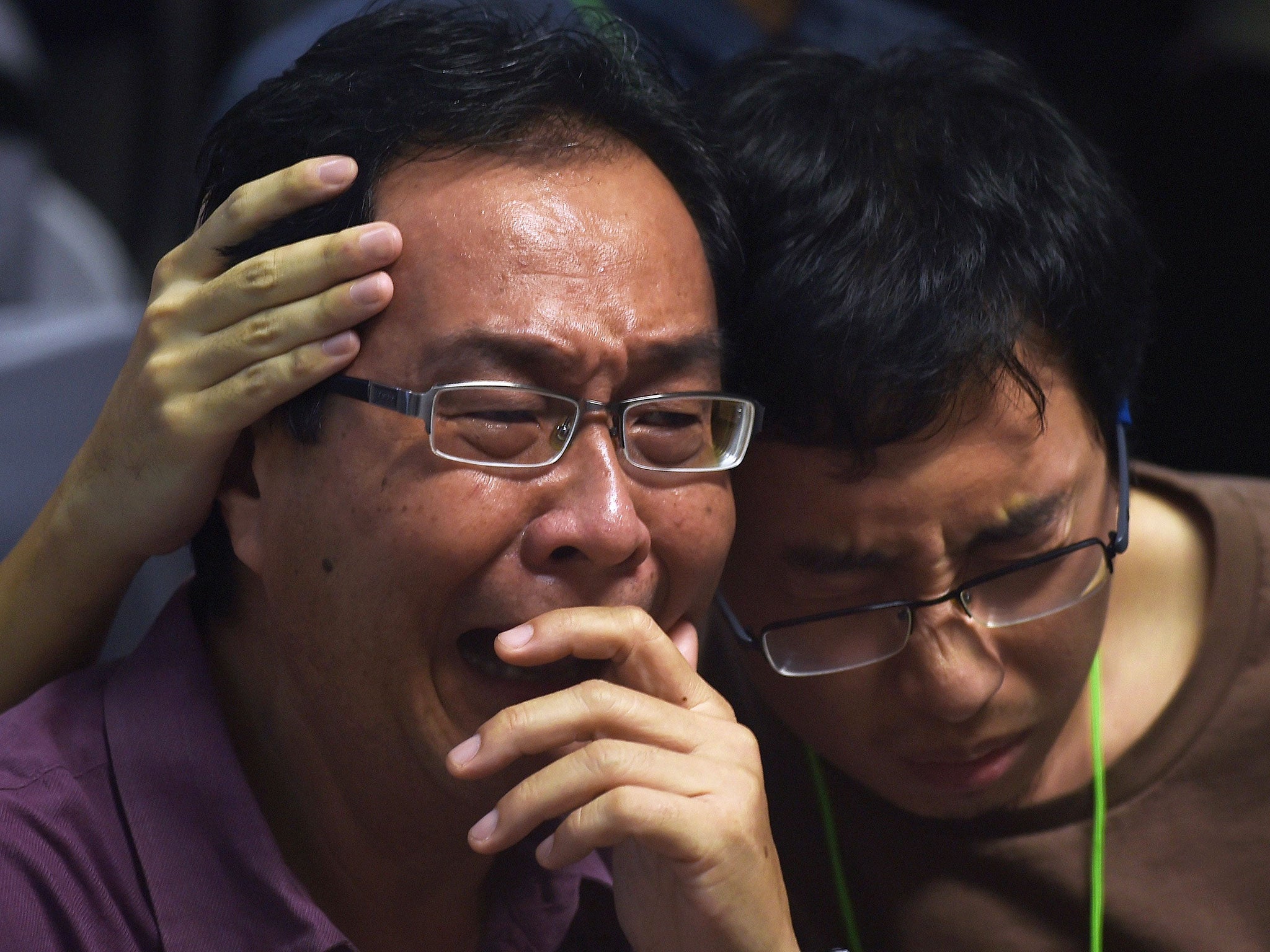 Family members of passengers onboard the missing Malaysian air carrier AirAsia flight QZ8501 react after watching news reports showing an unidentified body floating in the Java sea, inside the crisis-centre set up at Juanda International Airport in Suraba