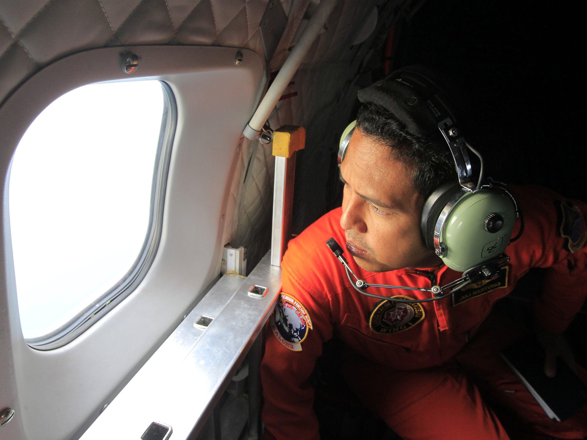 An Indonesia's Air Force crewman looks out of the window during a search and rescue operation as they search for the missing AirAsia plane in Indonesia