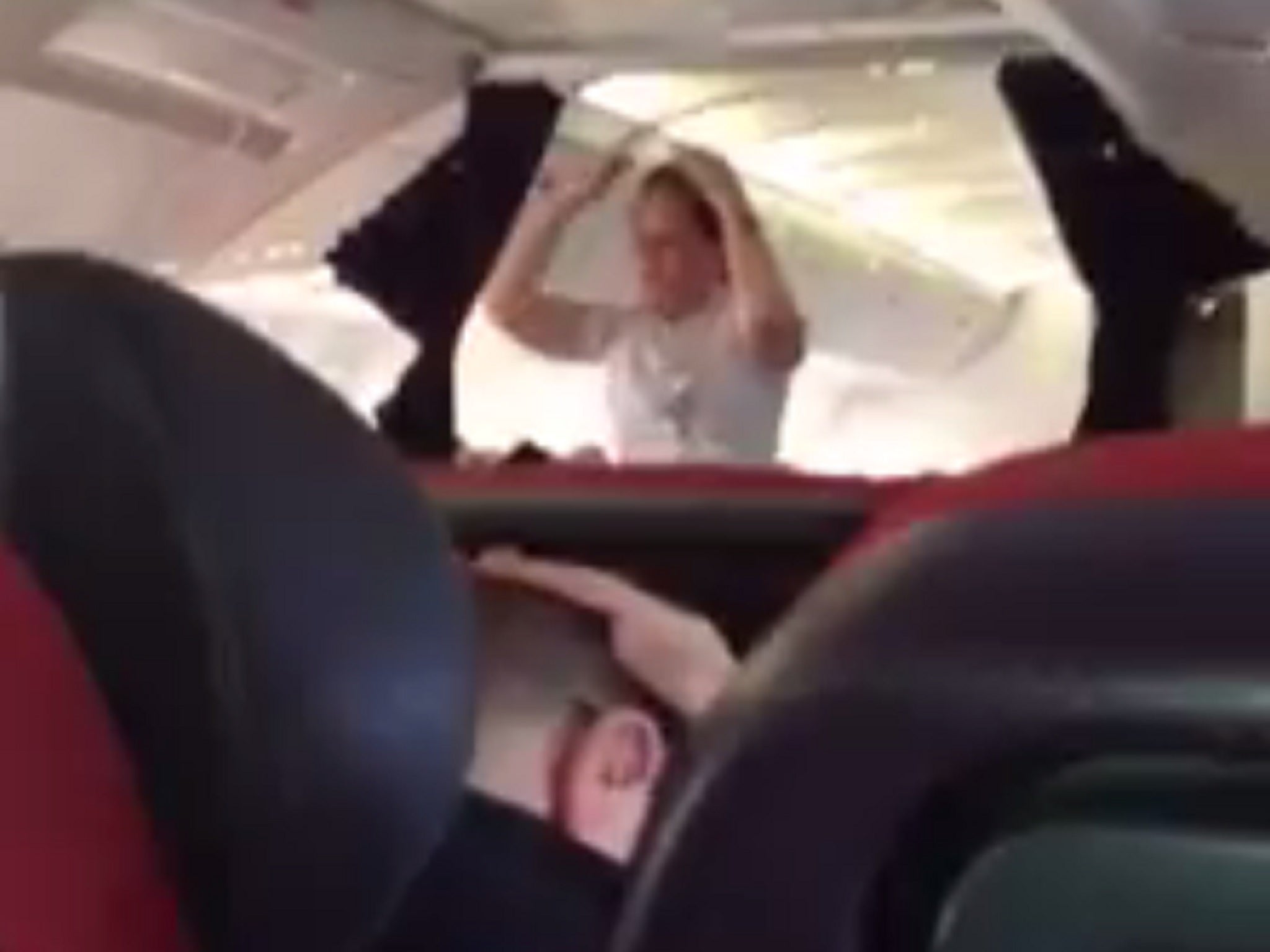 A man is seen practicing the safety position on the Virgin flight