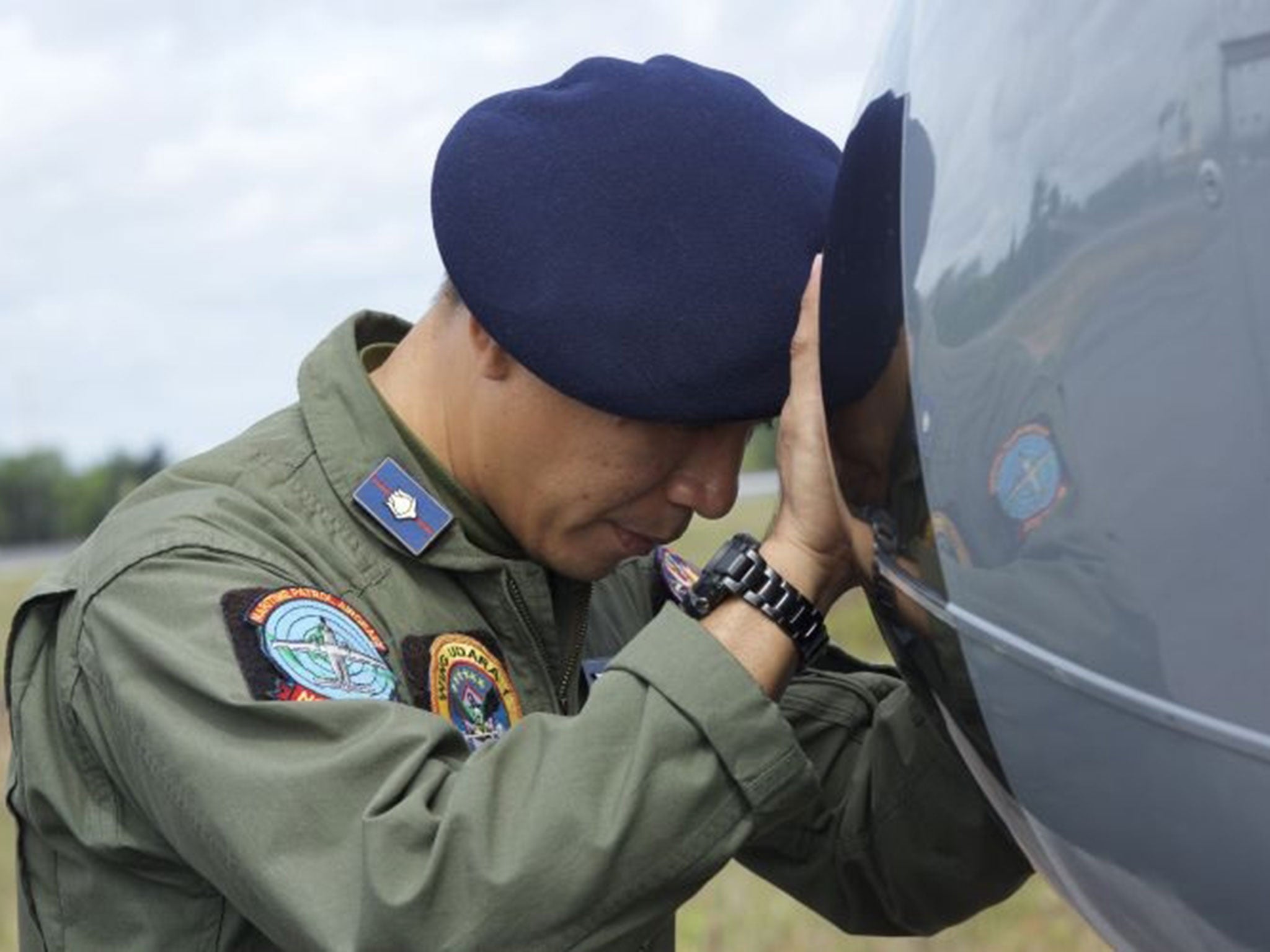 An Indonesian Navy airman prays on his plane before searching the waters near Bangka Island for debris from AirAsia Flight QZ8501