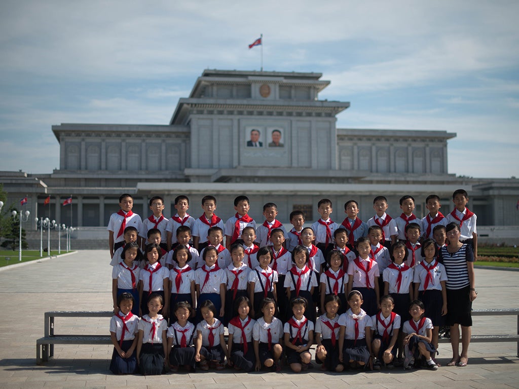 North Korean school children pose for a group photo before the portraits of late North Korean leaders Kim Il-Sung (top L) and Kim Jong-Il (top R) at the Kumsusan Palace of the Sun mausoleum in Pyongyang, July 2013