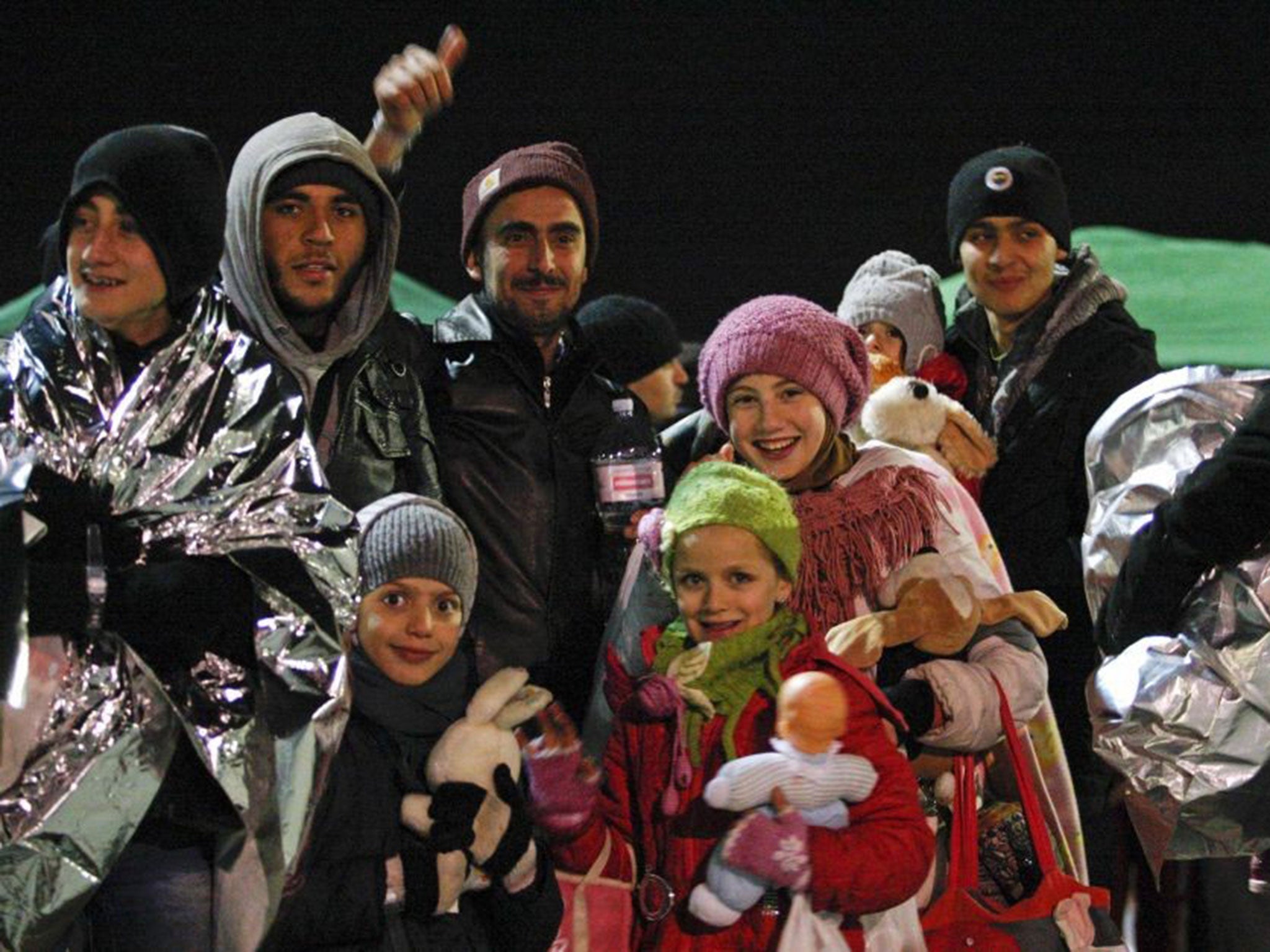 Migrants smile after disembarking from the Ezadeen at Corigliano Calabro harbour on 3 January