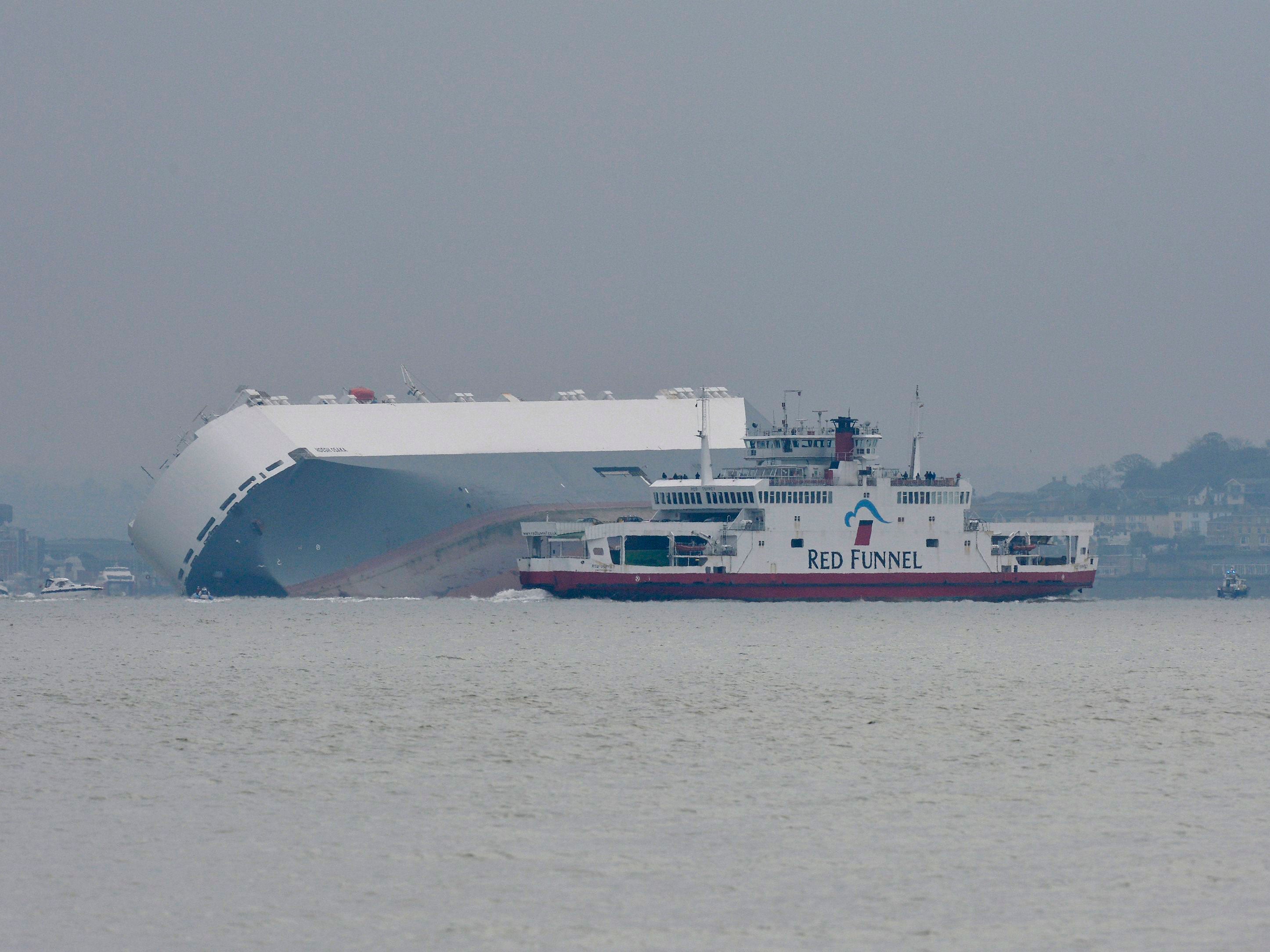 A Red Funnel Red Jet Hi-Speed ferry passes the Hoegh Osaka, a car carrier, after the ship became stranded on Bramble Bank, in the Solent (PA)