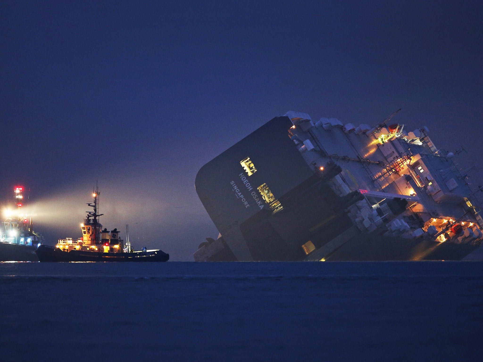 A salvage tug lights the hull of the stricken Hoegh Osaka cargo ship after it ran aground on a sand bank in the Solent in Cowes. The cargo ship ran aground on Bramble Bank after leaving Southampton bound for Germany. All 25 crew members were rescued overn