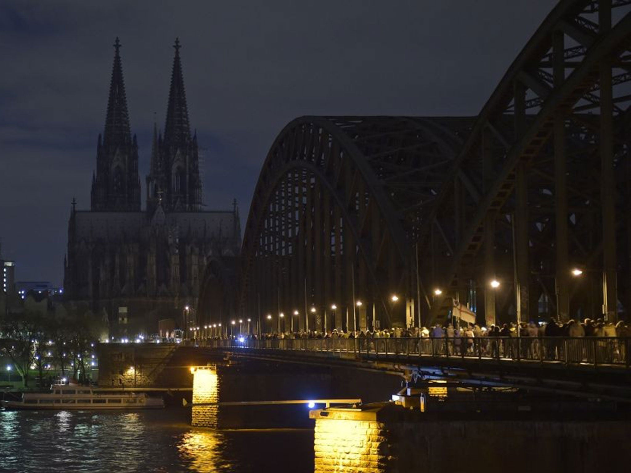 Anti-Pegida protesters march across a bridge in Cologne as the cathedral goes dark in support on 5 January