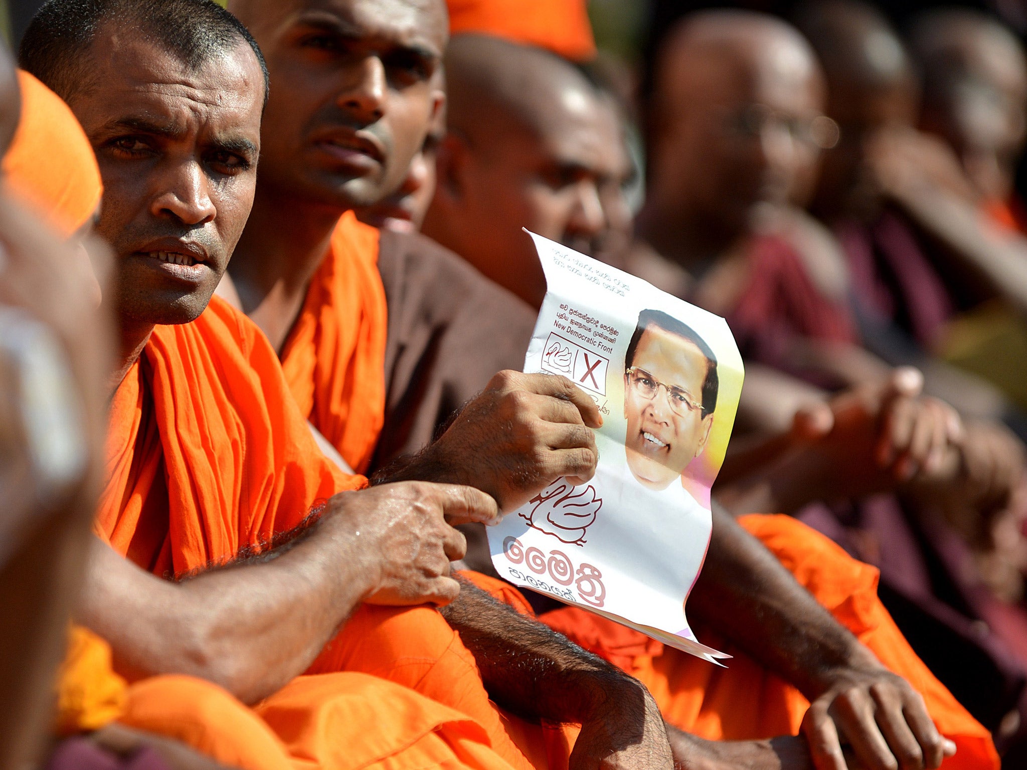 A Sri Lankan Buddhist monk holds up a leaflet featuring Maithripala Sirisena during a demonstration outside the official residence of President Mahinda Rajapakse in Colombo (AP)