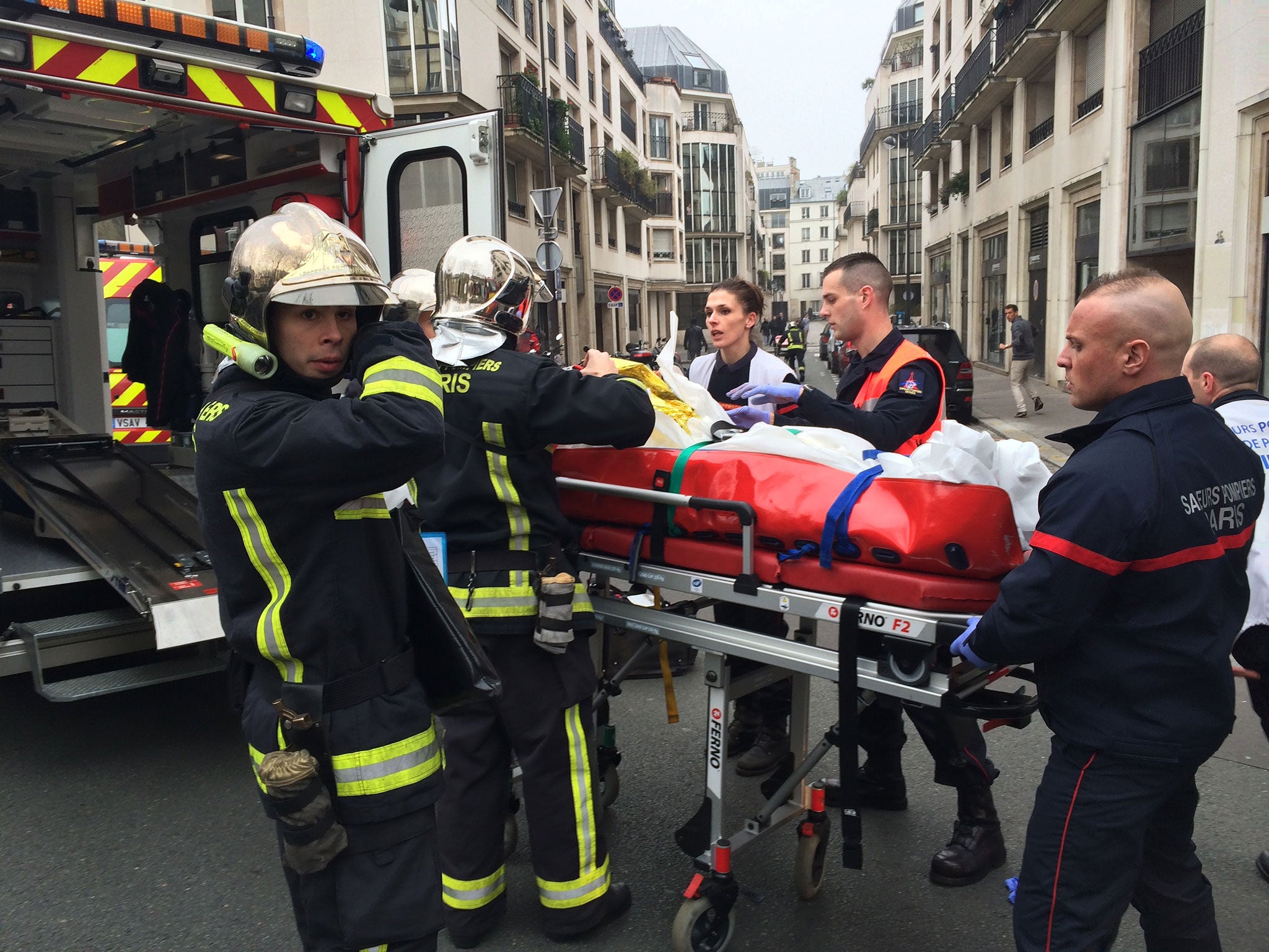 Firefighters carry an injured man on a stretcher in front of the offices of the French satirical newspaper Charlie Hebdo in Paris