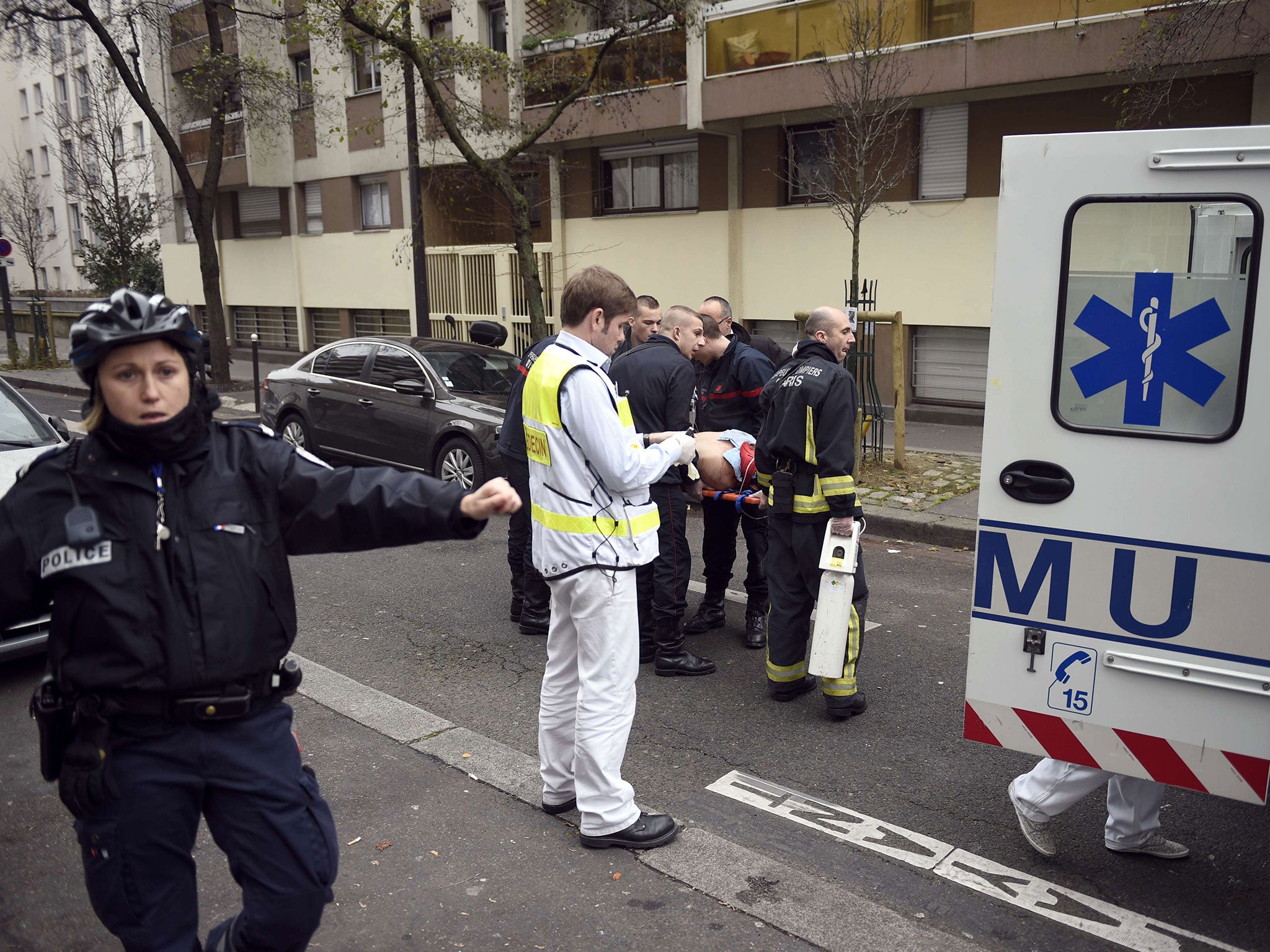 Firefighters carry an injured man on a stretcher in front of the offices of the French satirical newspaper Charlie Hebdo in Paris