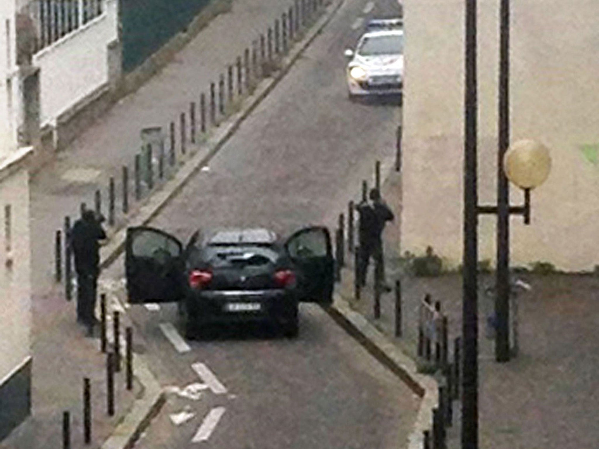 Armed gunmen face police officers near the offices of the French satirical newspaper Charlie Hebdo in Paris