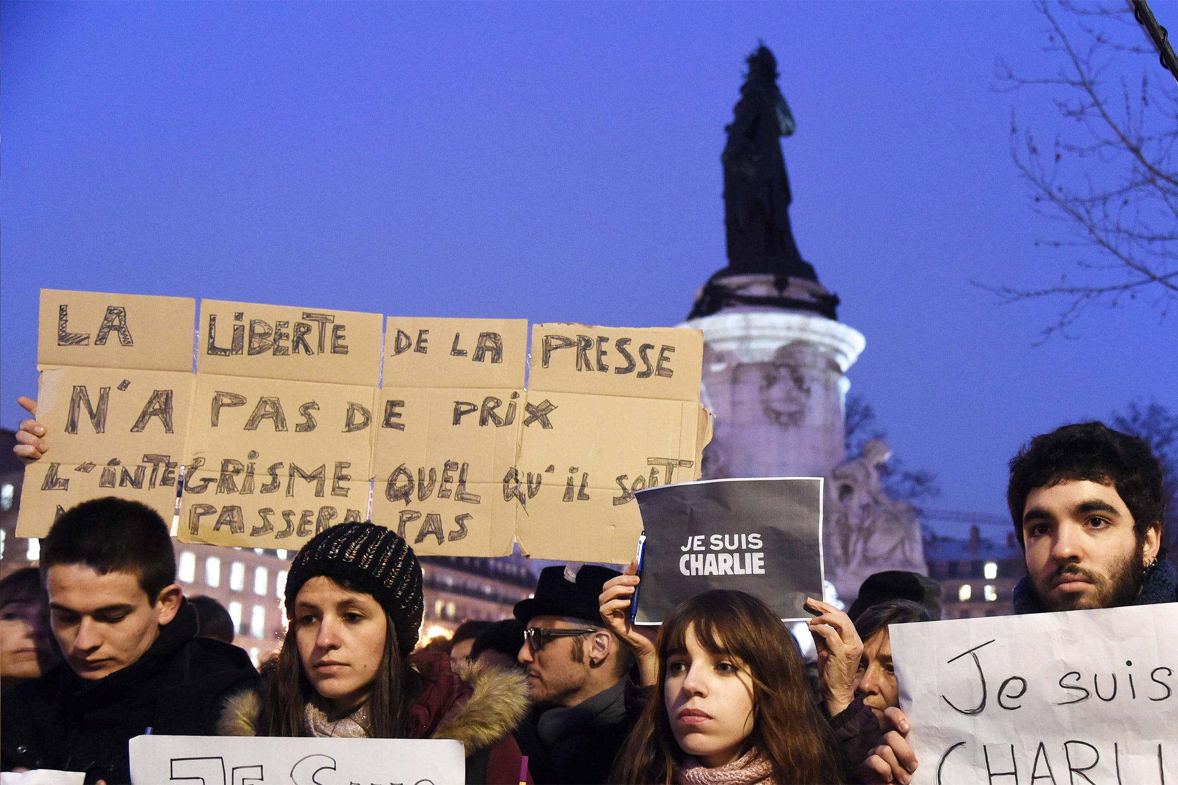 A man holds a placard reading: 'Freedom of the press is priceless, fundamentalism, of any kind, will not pass' as others hold up placards reading in French, 'I am Charlie' during a gathering at the Place de la Republique in Paris (Getty)