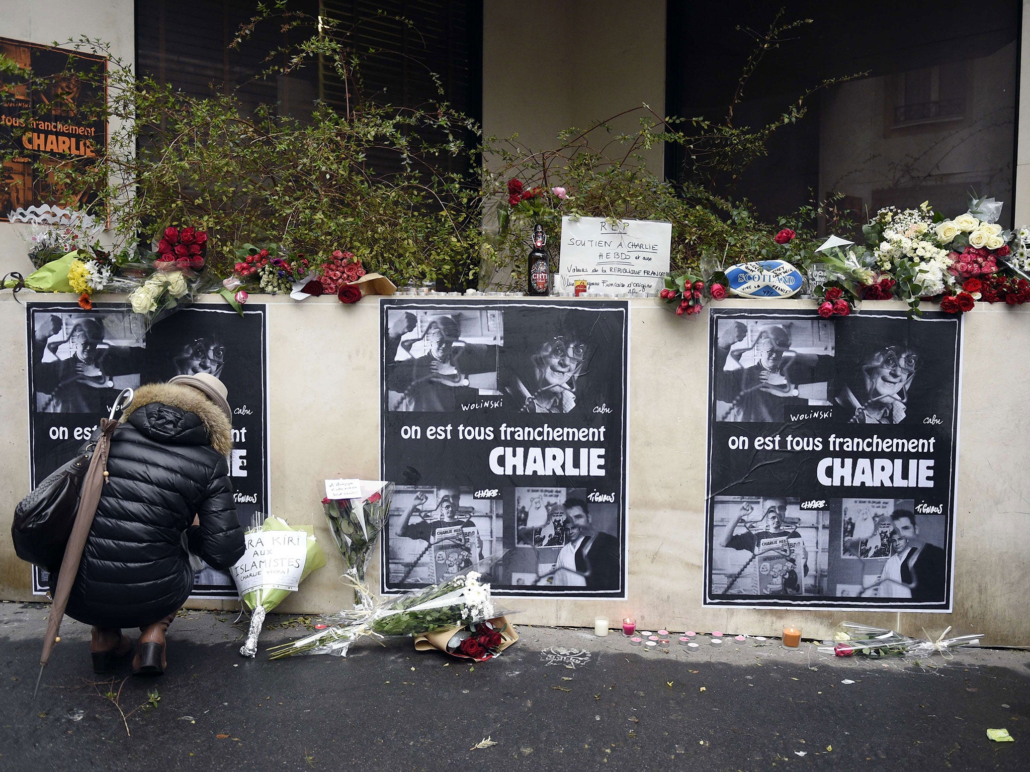 A woman places flowers near the offices of French satirical newspaper Charlie Hebdo in Paris