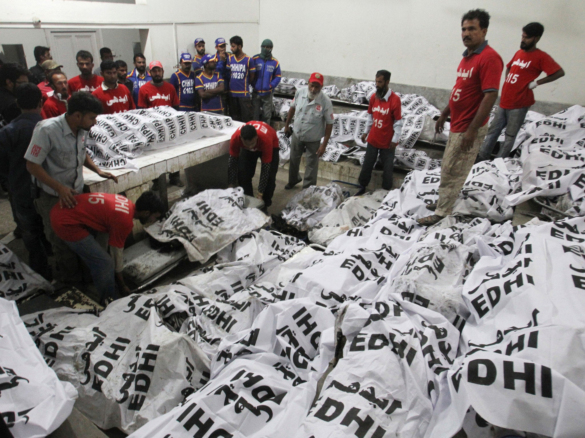 Pakistani rescue workers gather around the bodies of bus accident victims in a hospital in Karachi, Pakistan (AP)